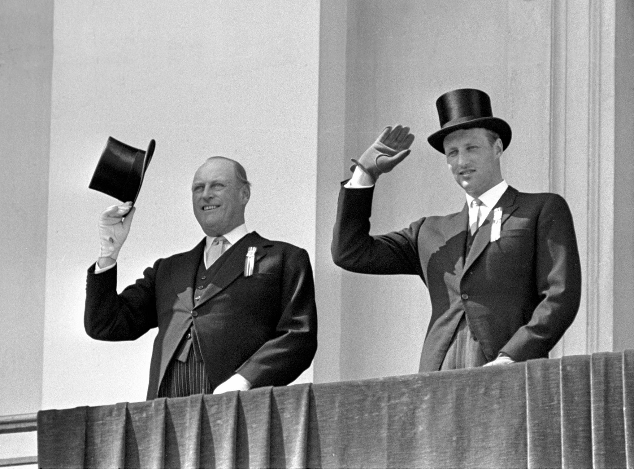 Kong Olav (t.v) og kronprins Harald på Slottsbalkongen i 1966. Kongen hilser med flosshatten. Harald med flosshatt på hodet. ARKIVFOTO: SCANPIX