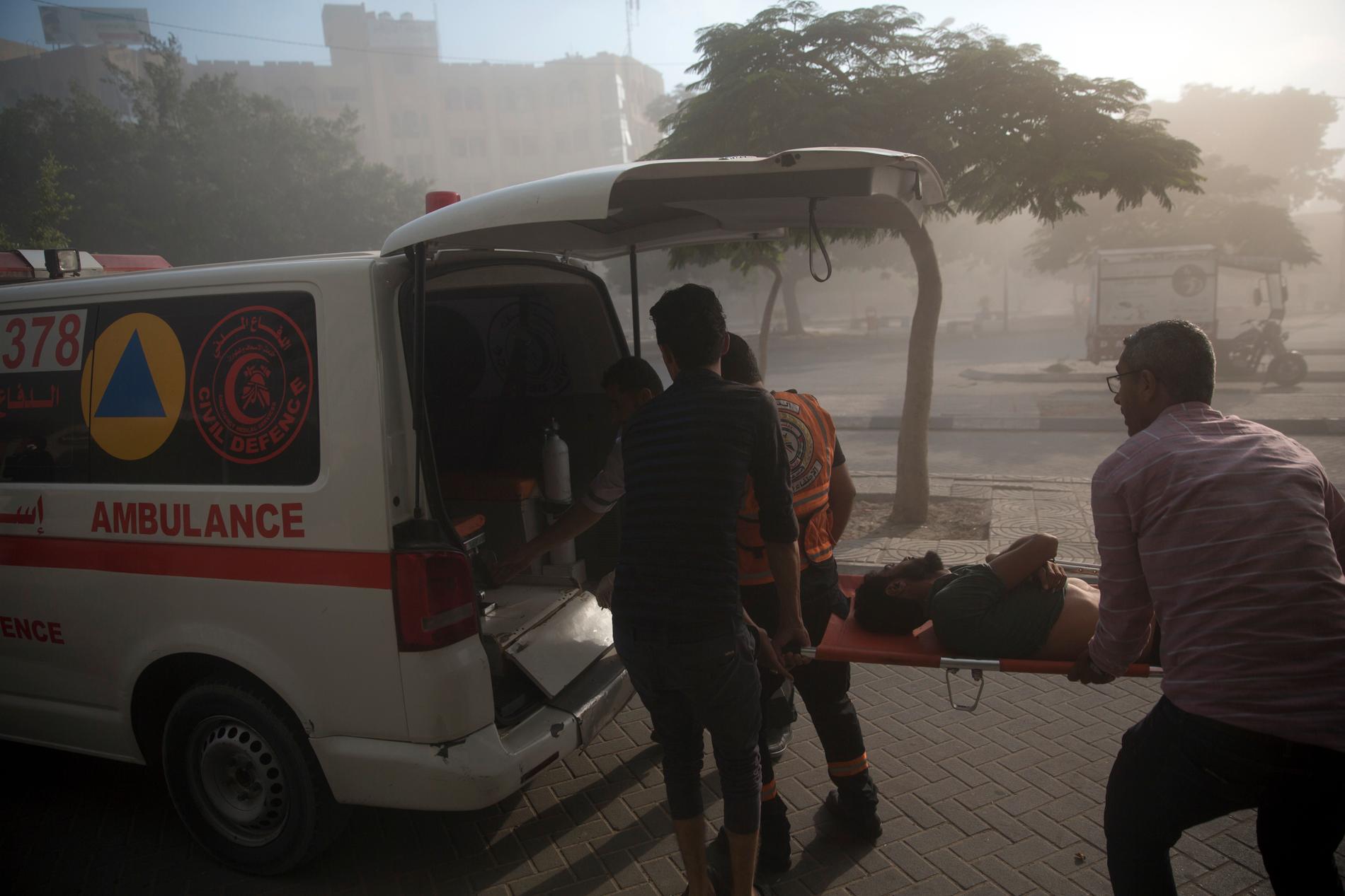 En såret palestinsk mann evakueres etter at et israelsk luftangrep traff en offentlig bygning i Gaza by lørdag. Foto: Khalil Hamra / AP / NTB scanpix