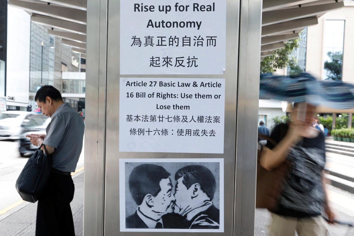 Et arrangert fotografi klistret opp på en buss-stasjon, forestiller Xi Jinping som kysser Hongkongs chief executive CY Leung. Teksten er en oppfordring til hongkongerne om å engasjere seg for reelt selvstyre. 