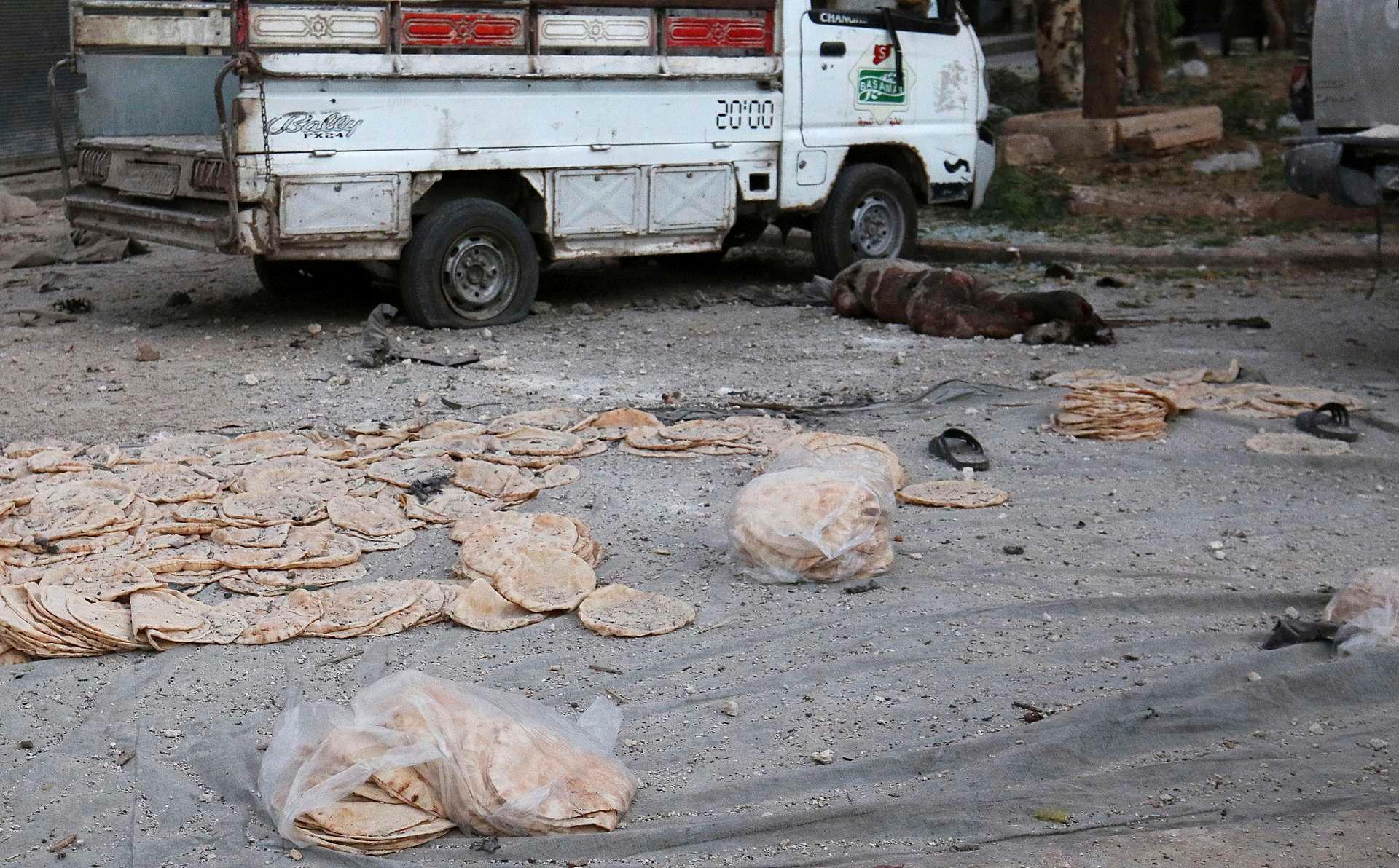 Det flate syriske brødet ligger strødd ut over plassen foran et bakeri i det opprørskontrollerte Bab al-Maqam-distriktet i Aleppo. En person som ble drept i et artilleriangrep natt til onsdag ligger død på bakken.