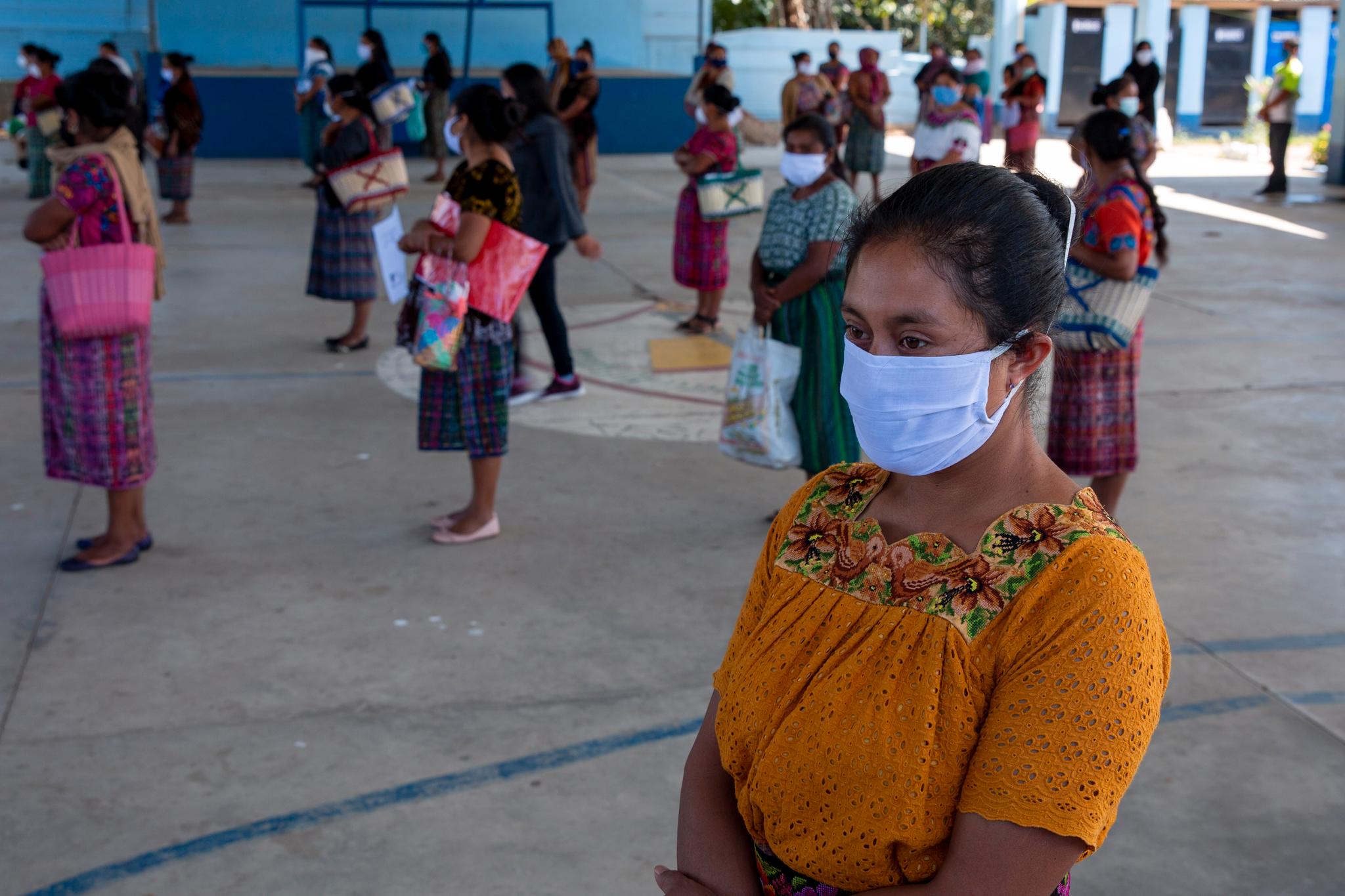 Disse kvinnene fra en urfolksbefolkning i Xesui, Guatemala holder god avstand der de står i kø for å få utdelt mat til barna. 