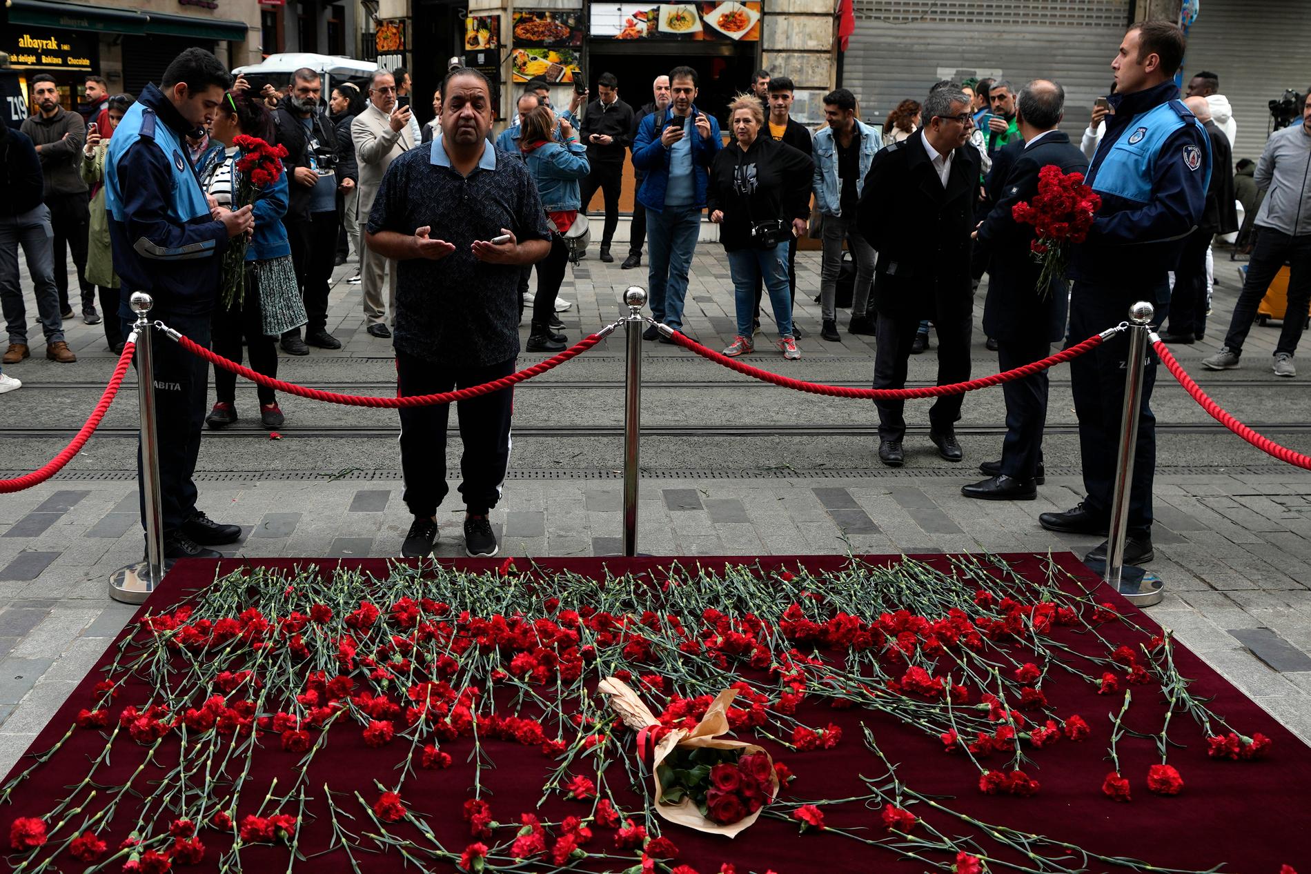 Folk legger ned blomster mandag på stedet der minst seks mennesker ble drept i en bombeeksplosjon i Istanbul søndag. En kvinne er pågrepet og siktet for angrepet. 