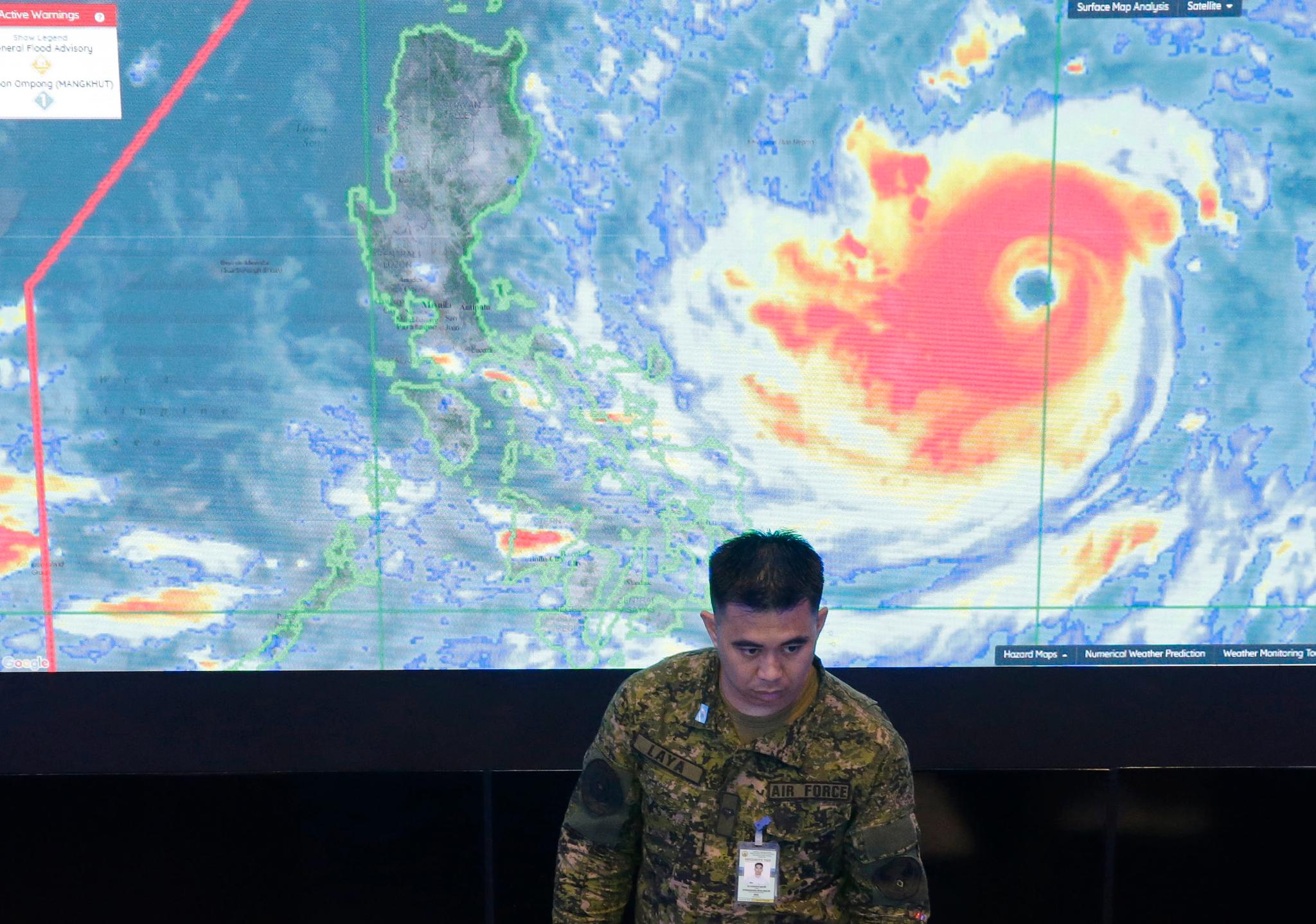 En medarbeider i det filippinske luftforsvaret står foran et satellittbilde av monstertyfonen Mangkhut, som de neste dagene truer med å skape massive ødeleggelser og kaos i Asia. Filippinene er ventet å bli rammet natt til lørdag lokal tid.