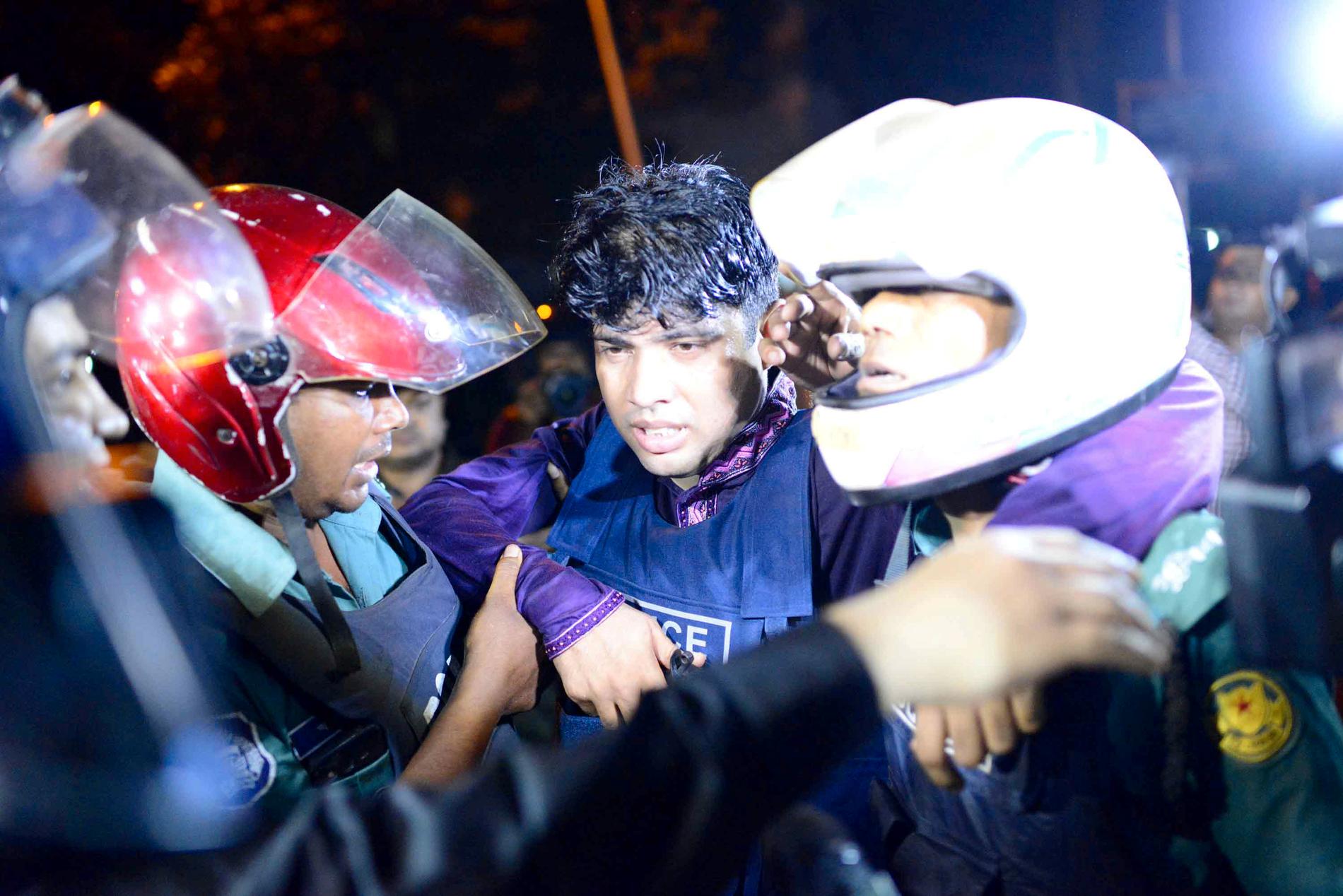SKADET: En skadet politimann blir fraktet ut fra området ved restauranten i Dhaka, Bangladeshs hovedstad.