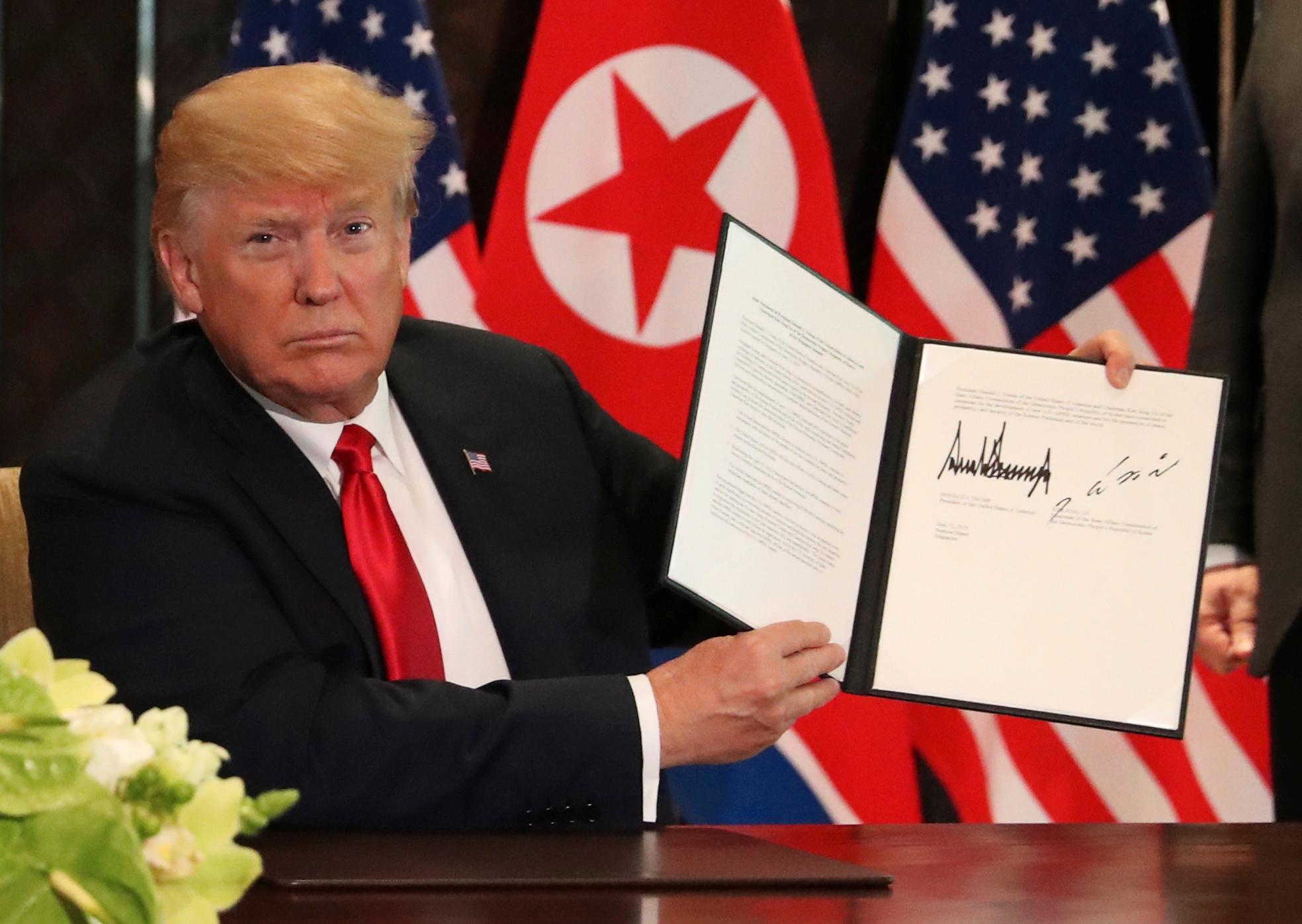  USAs president Donald Trump viser frem dokumentet som han og Nord-Koreas leder Kim Jong-un nettopp har signert på Capella resort på Sentosa Island i Singapore tirsdag 12. juni. 