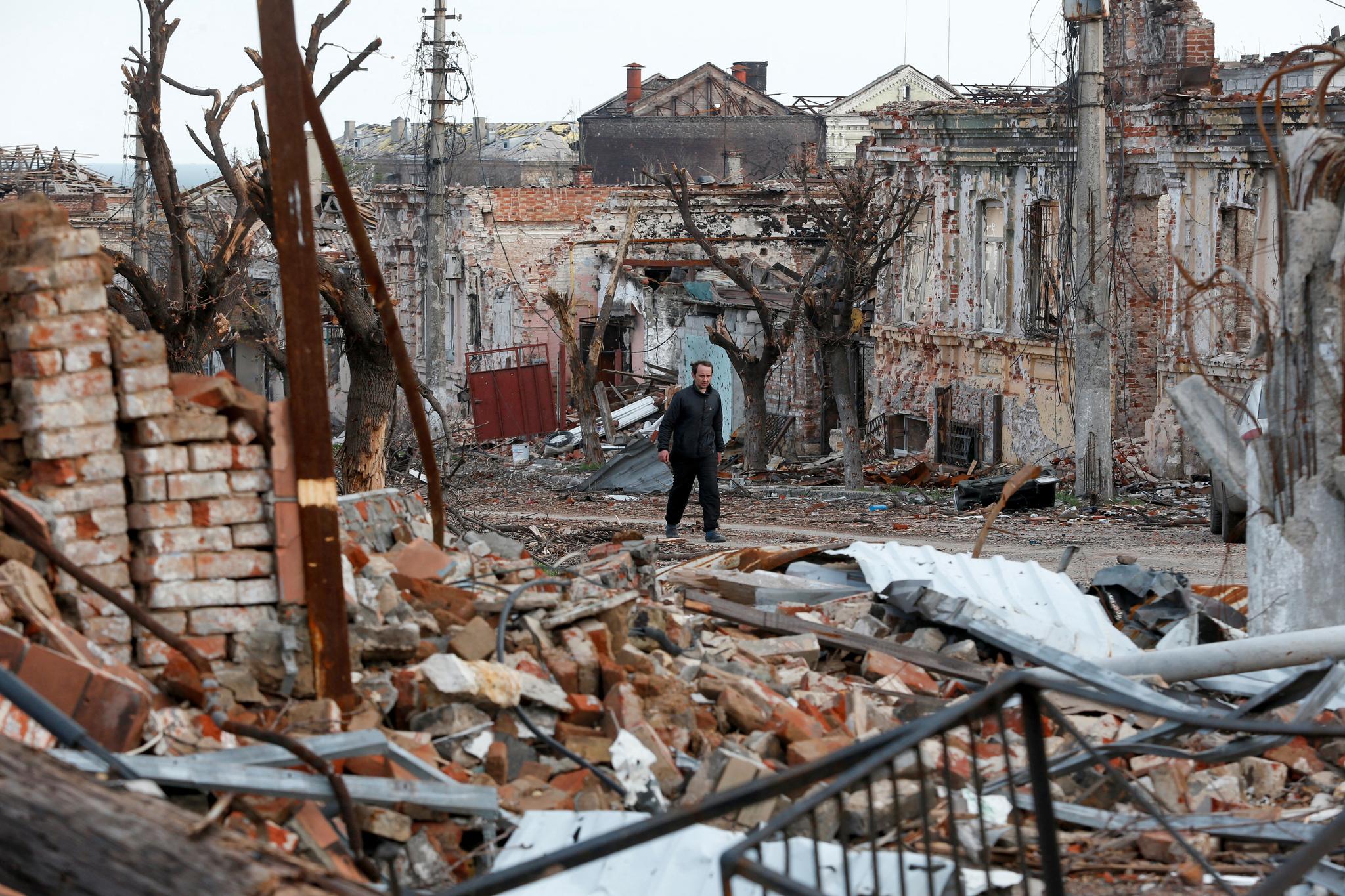 En mann går i nærheten av skadede bygninger i Mariupol, fredag 22. april 2022.
