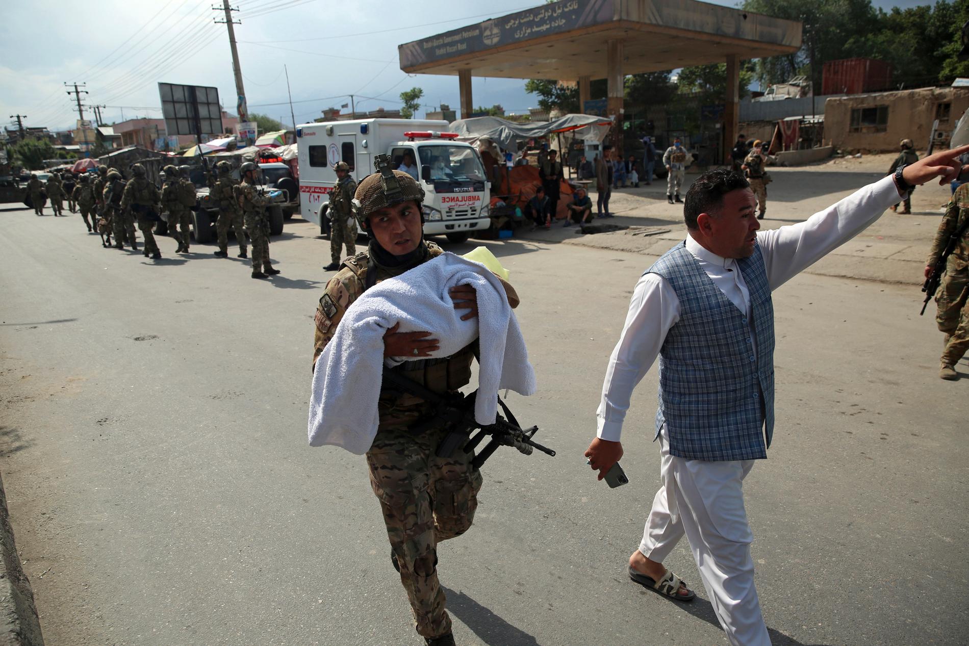 En afghansk soldat bærer en baby etter sykehusangrepet i Afghanistans hovedstad Kabul tirsdag. 