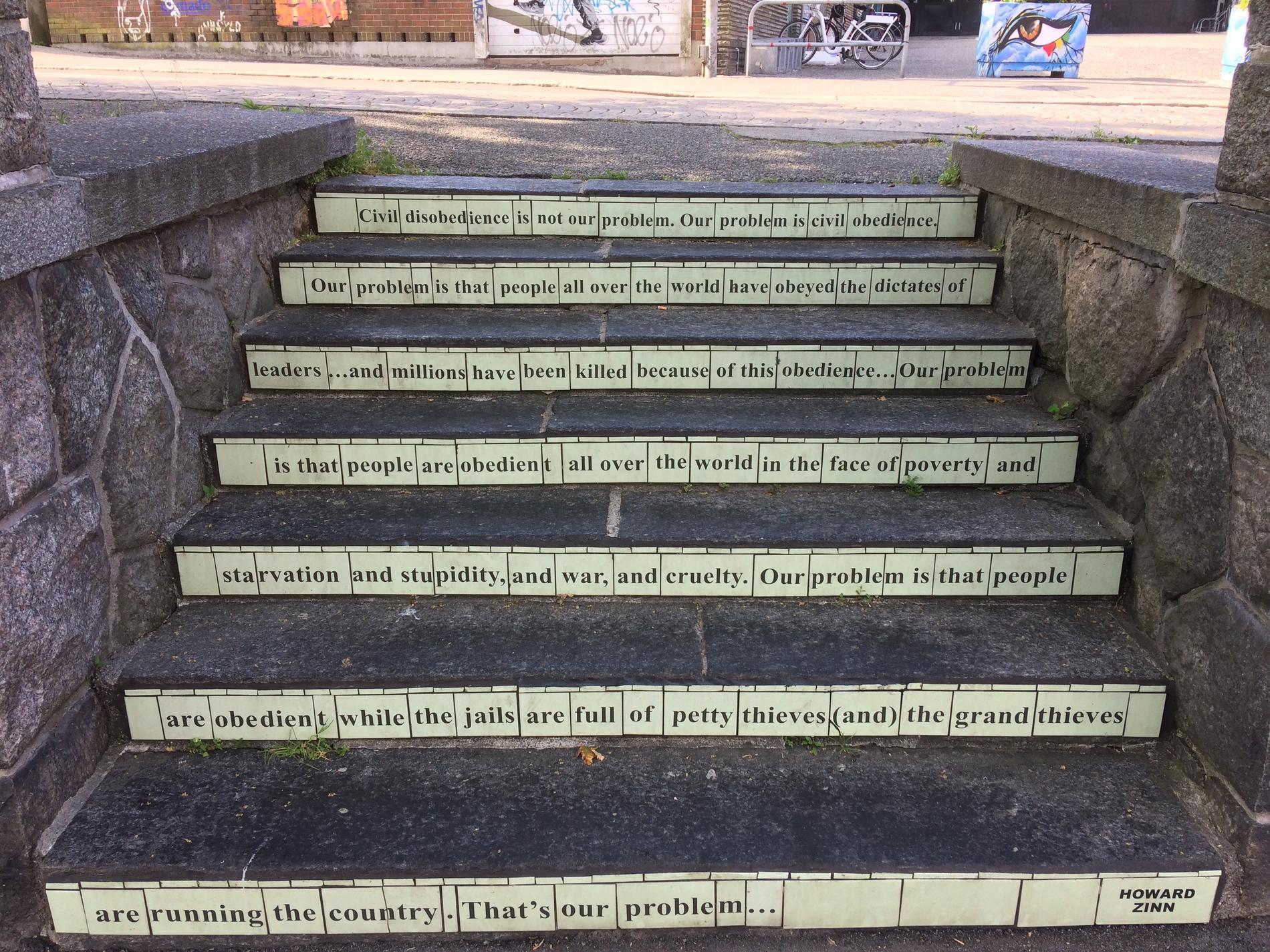 Dette noe uvanlige gatekunstverket er laget av keramikk og man finner det på en av trappene på Nytorget. Teksten er et sitat fra Howard Zinn, og kunstneren er Carrie Reichardt fra Storbritannia.