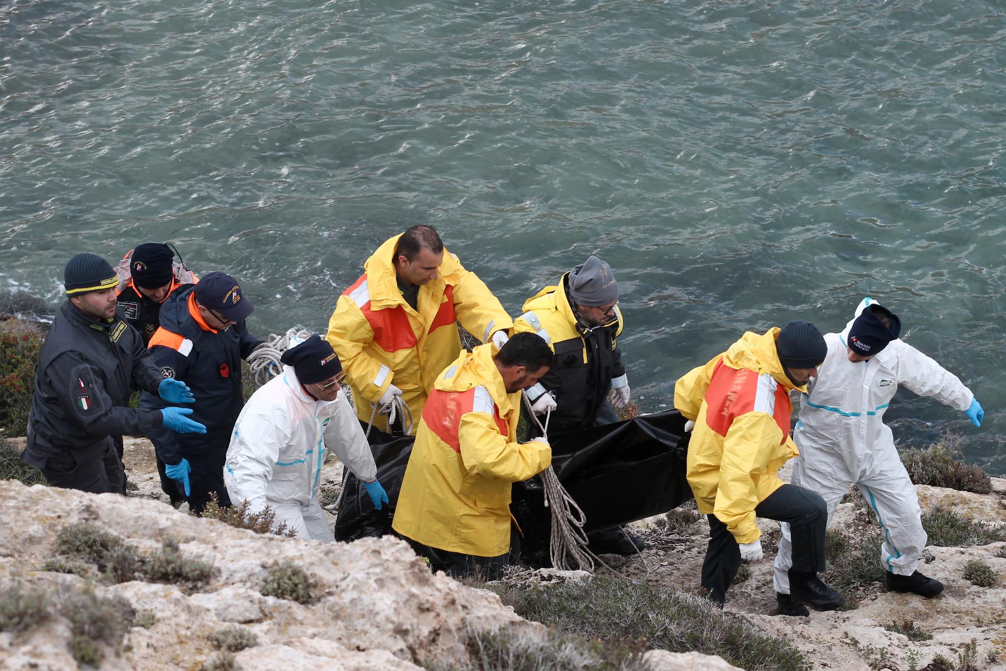 Redningsmannskap frakter vekk en omkommet person etter kantringen ved Lampedusa lørdag. 