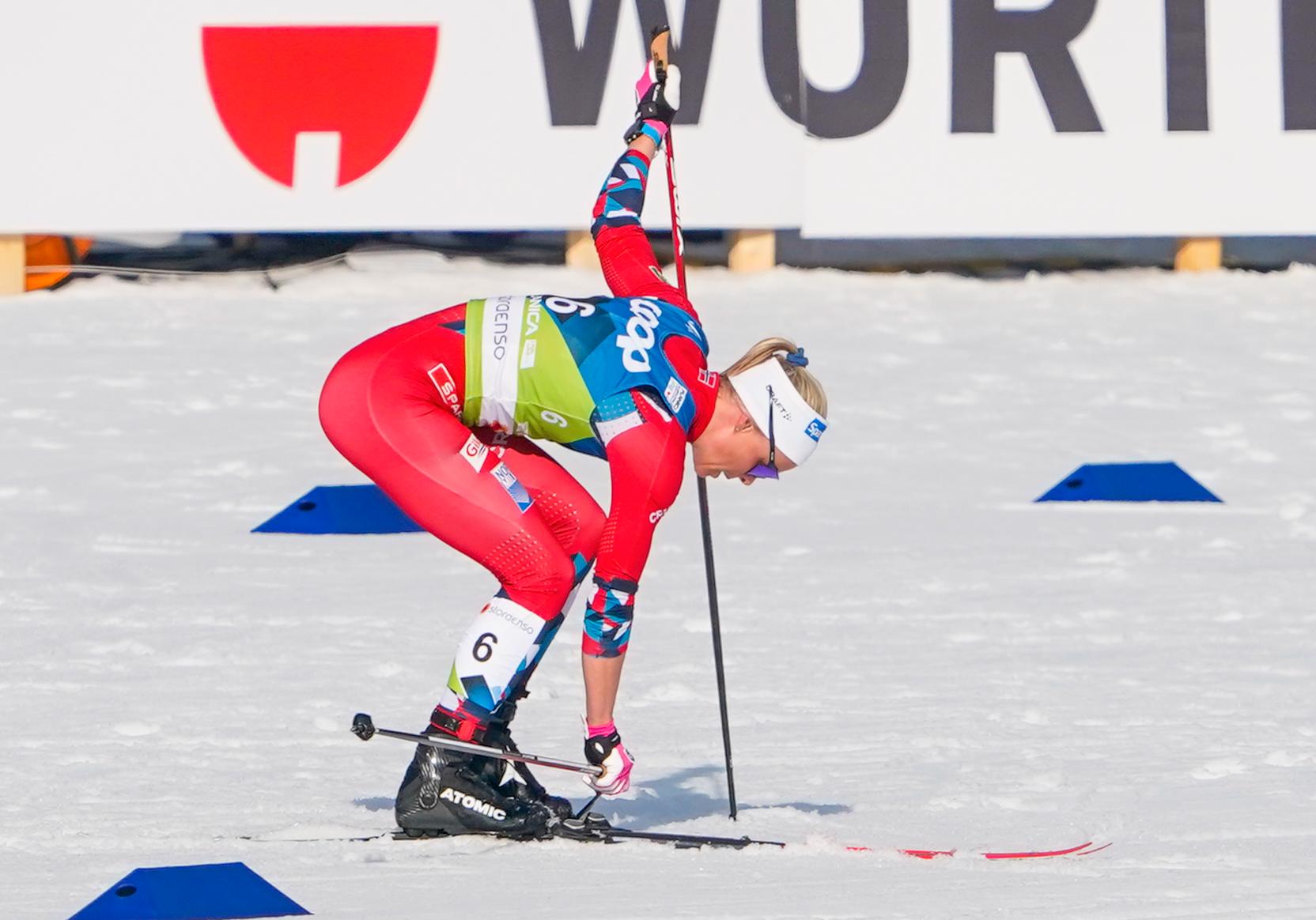TRØBBEL: Mens de andre utøverne setter ut i løypa, sliter Anne Kjersti Kalvå med å få satt bindingene i skien på lørdagens 15 kilometer med skibytte.