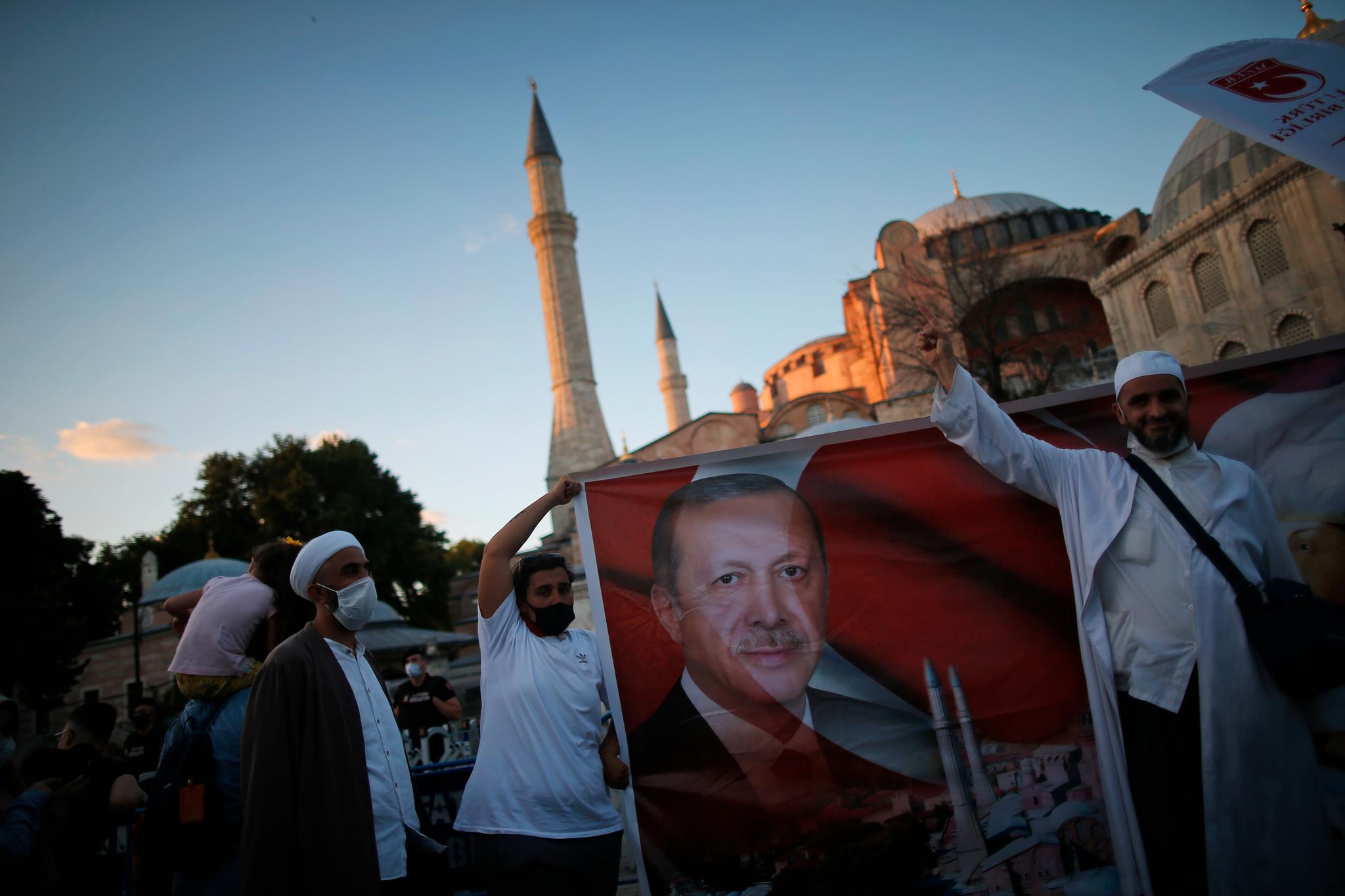 Tyrkere holder opp en plakat av president Recep Tayyip Erdogan utenfor Hagia Sofia etter at presidenten fredag omgjorde landemerket Hagia Sofia til moské. 