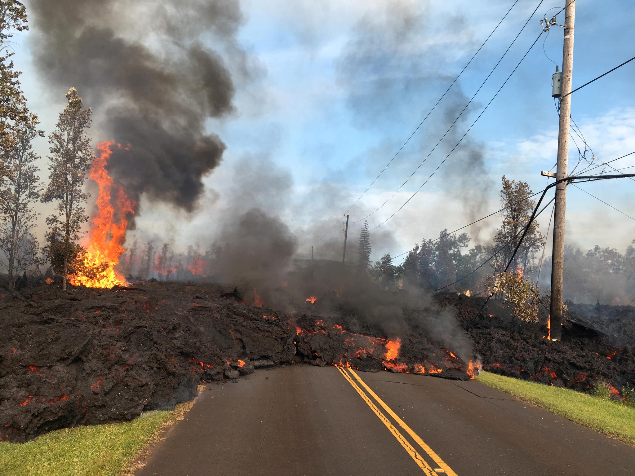 Glødende lava avanserer bortover veien i boligområdet. 