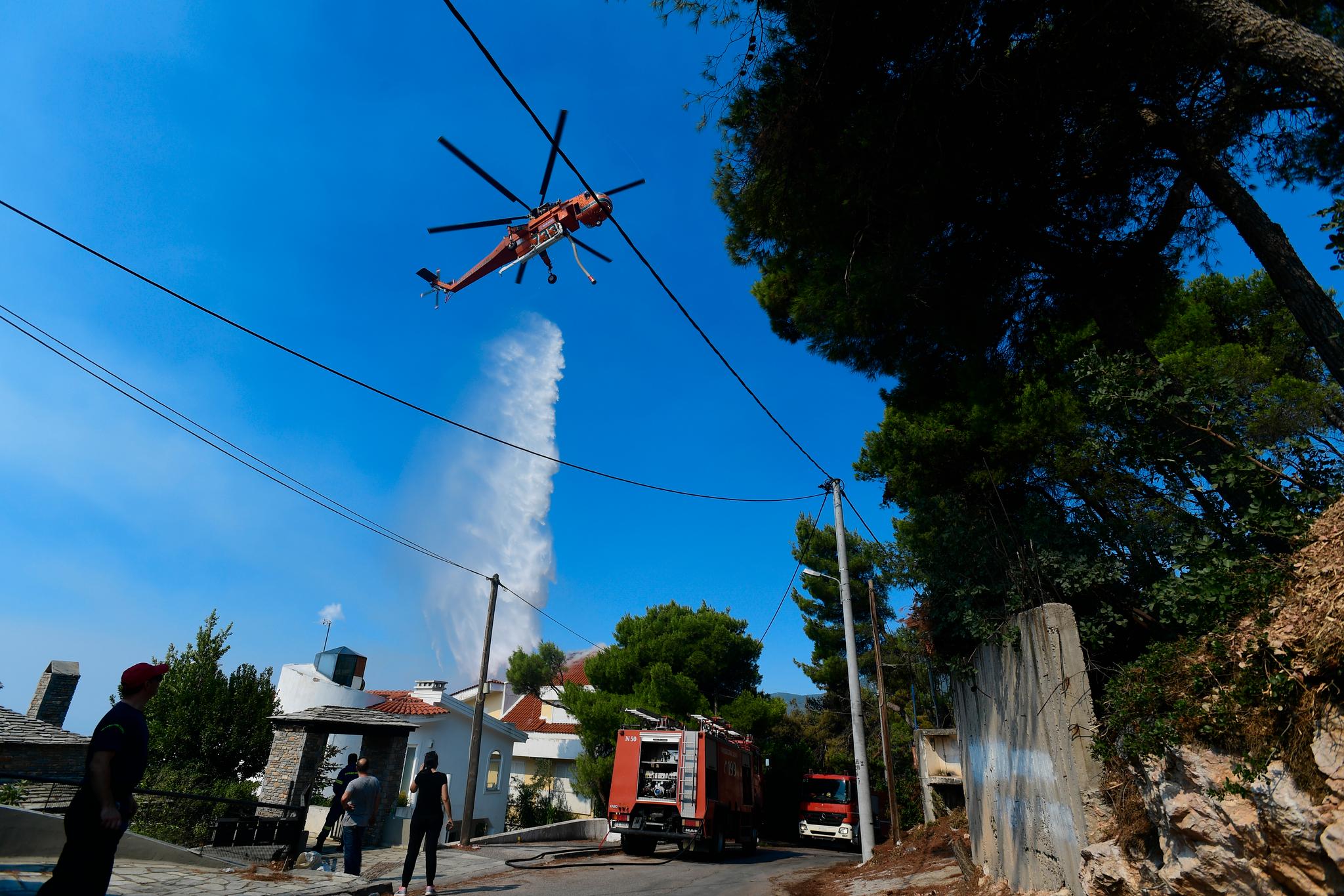 Et helikopter prøver å slukke brannen i et boligområde 25 kilometer nord for Athen.