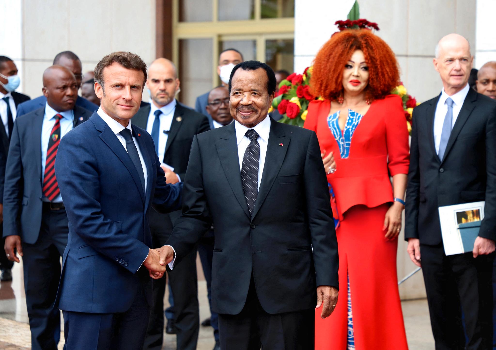 Frankrikes president Emmanuel Macron hilser på Kameruns president Paul Biya. Bak står Biyas kone, Chantal.