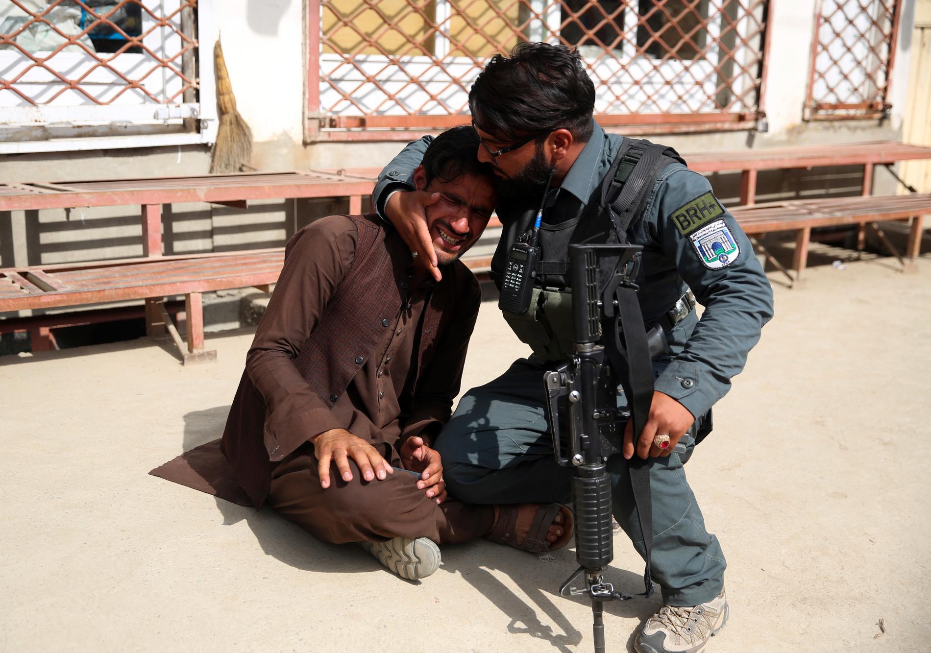 En afghansk politimann trøster en mann etter terrorangrepet mot et sykehus i Kabul tirsdag. 