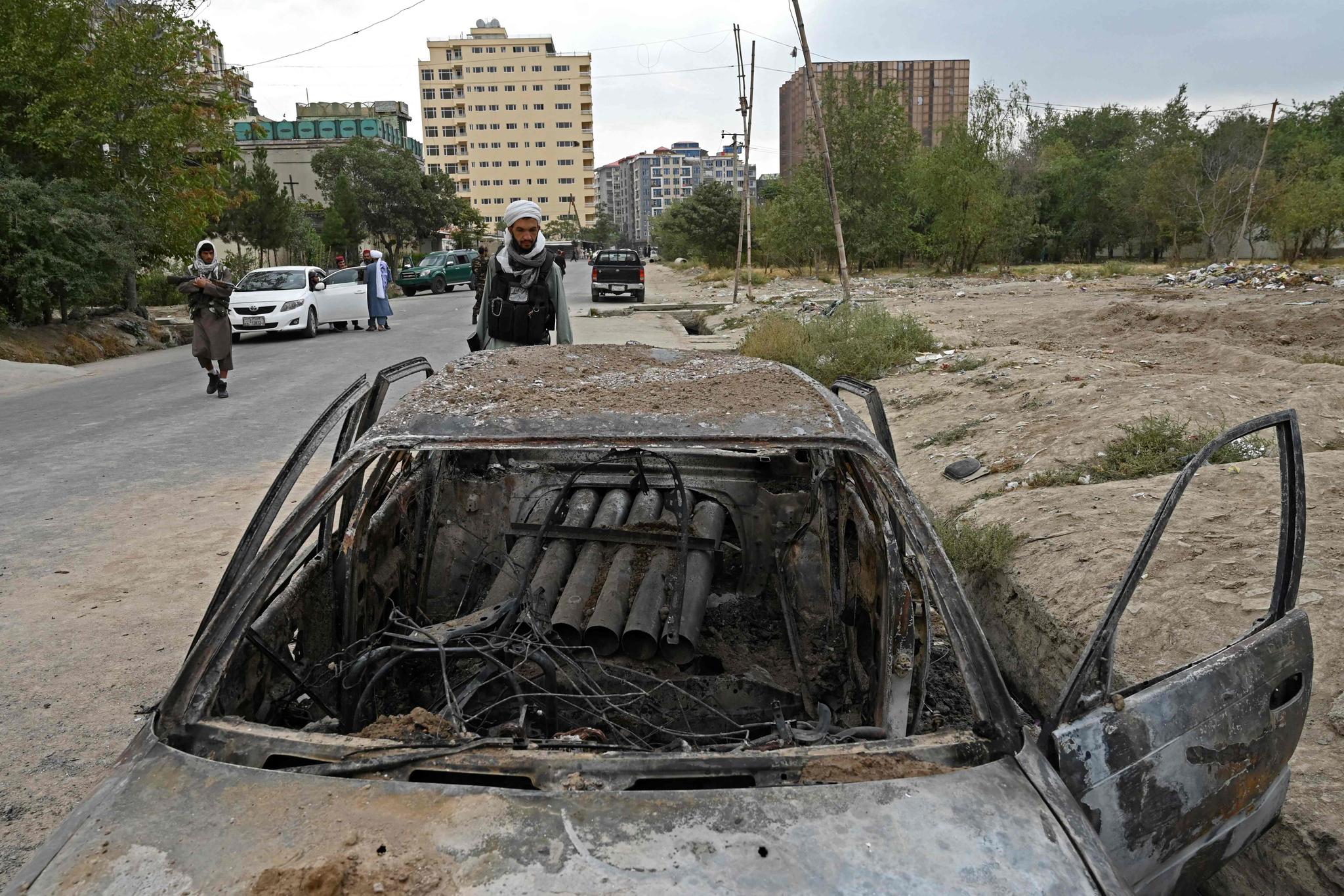 Taliban-soldater undersøker en ødelagt bil med det som ser ut til å være rakettoppskytingsutstyr at flere raketter ble avfyrt mot flyplassen i Kabul mandag morgen. 