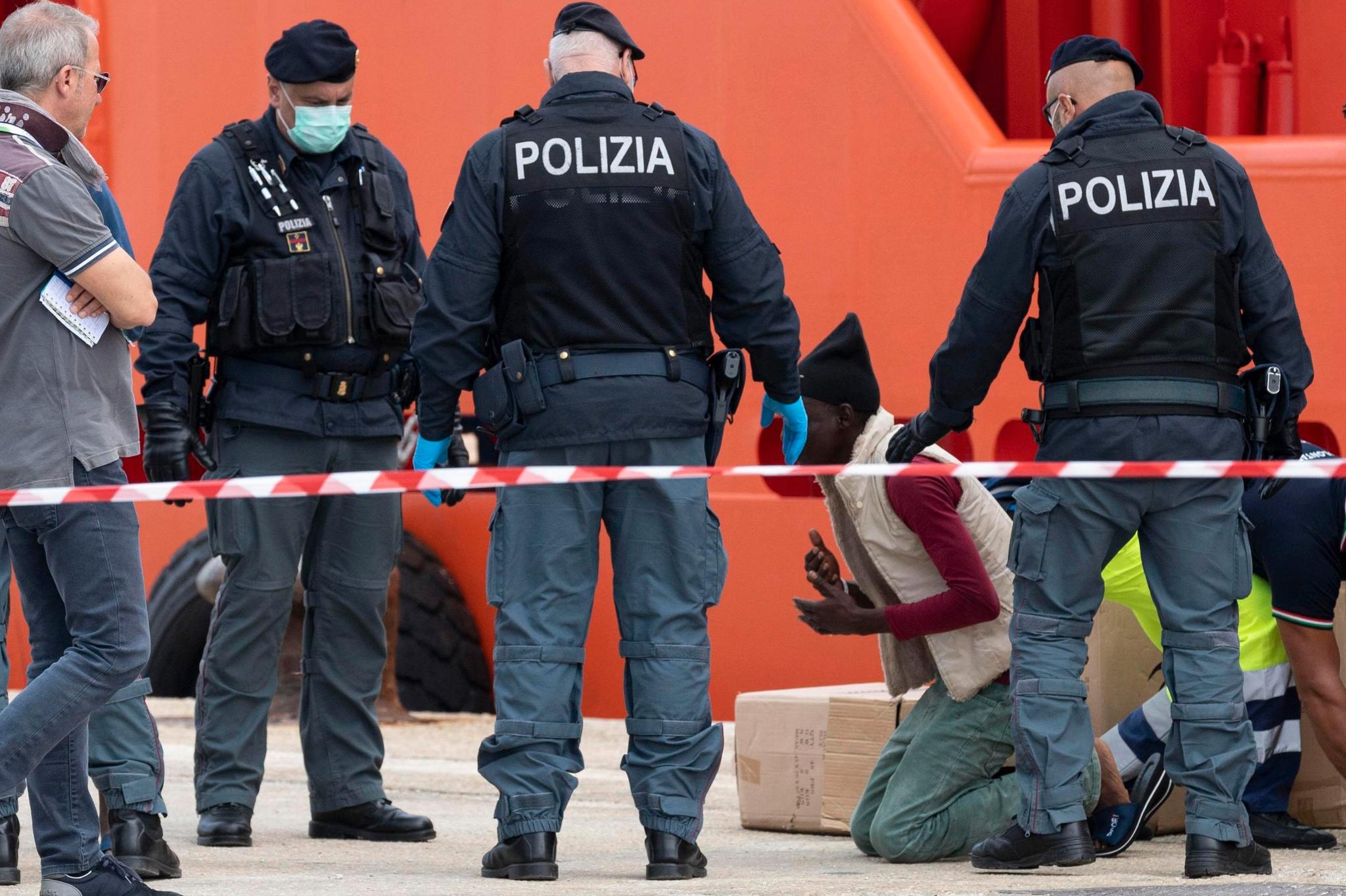 En migrant kneler i det han blir geleidet av en båt i den italienske havnen Pozzallo den 3. november.