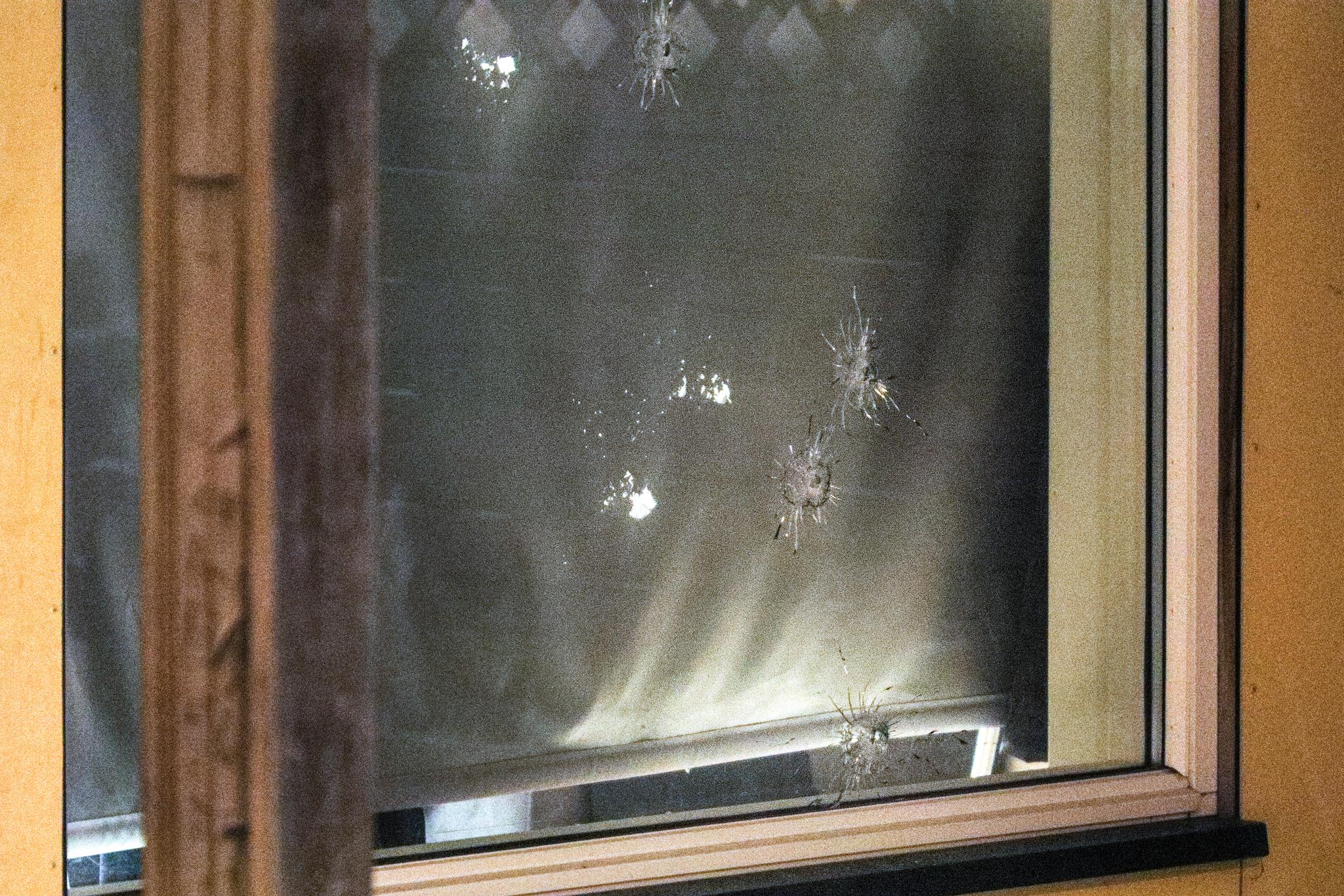 Det er tydelige kulehull både i vinduet og i et gardin innenfor. 