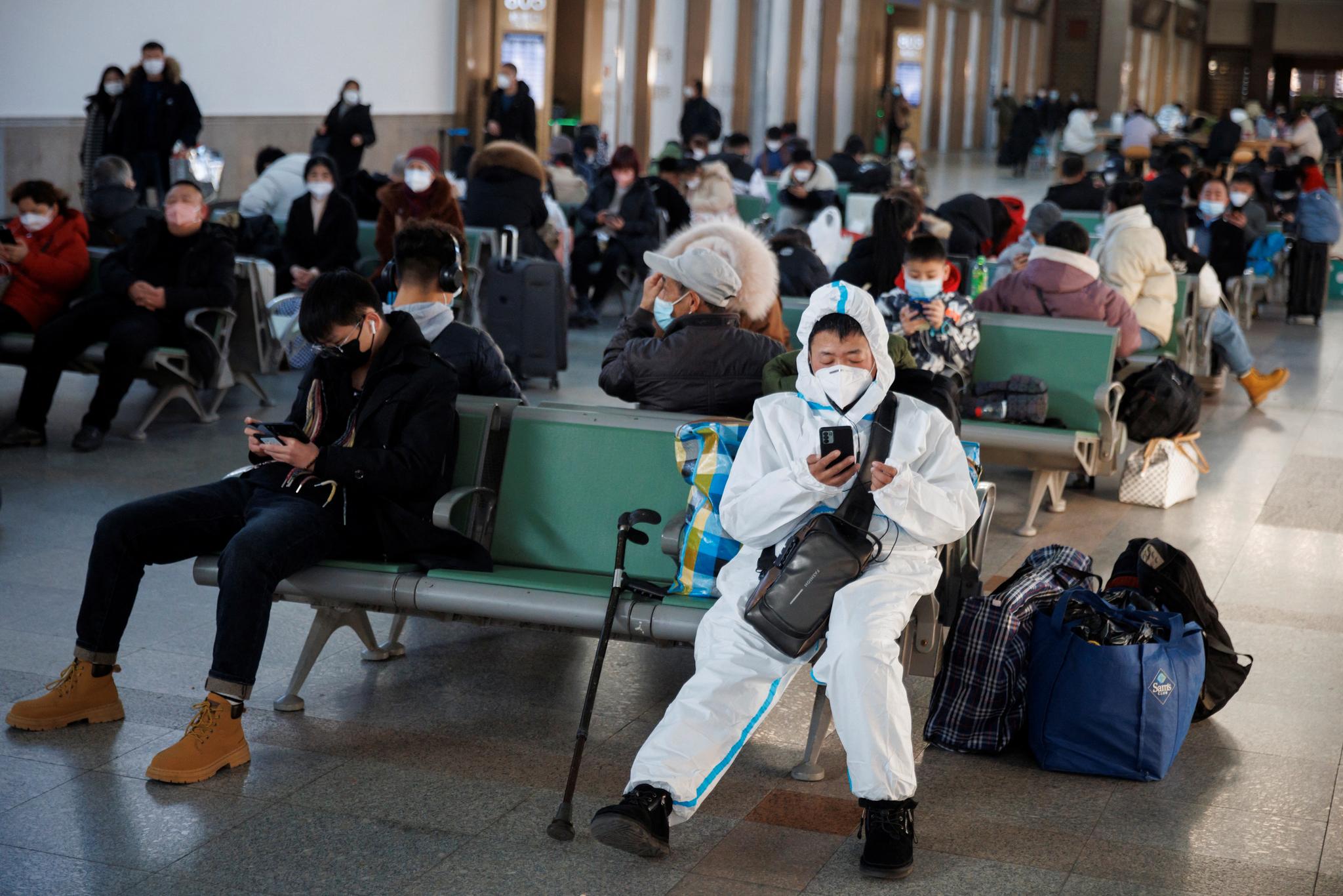 Smitteverntiltakene er i hovedsak fjernet i Kina, men noen velger likevel å sikre seg. Denne personen har helgardert seg på en togstasjon i Beijing.