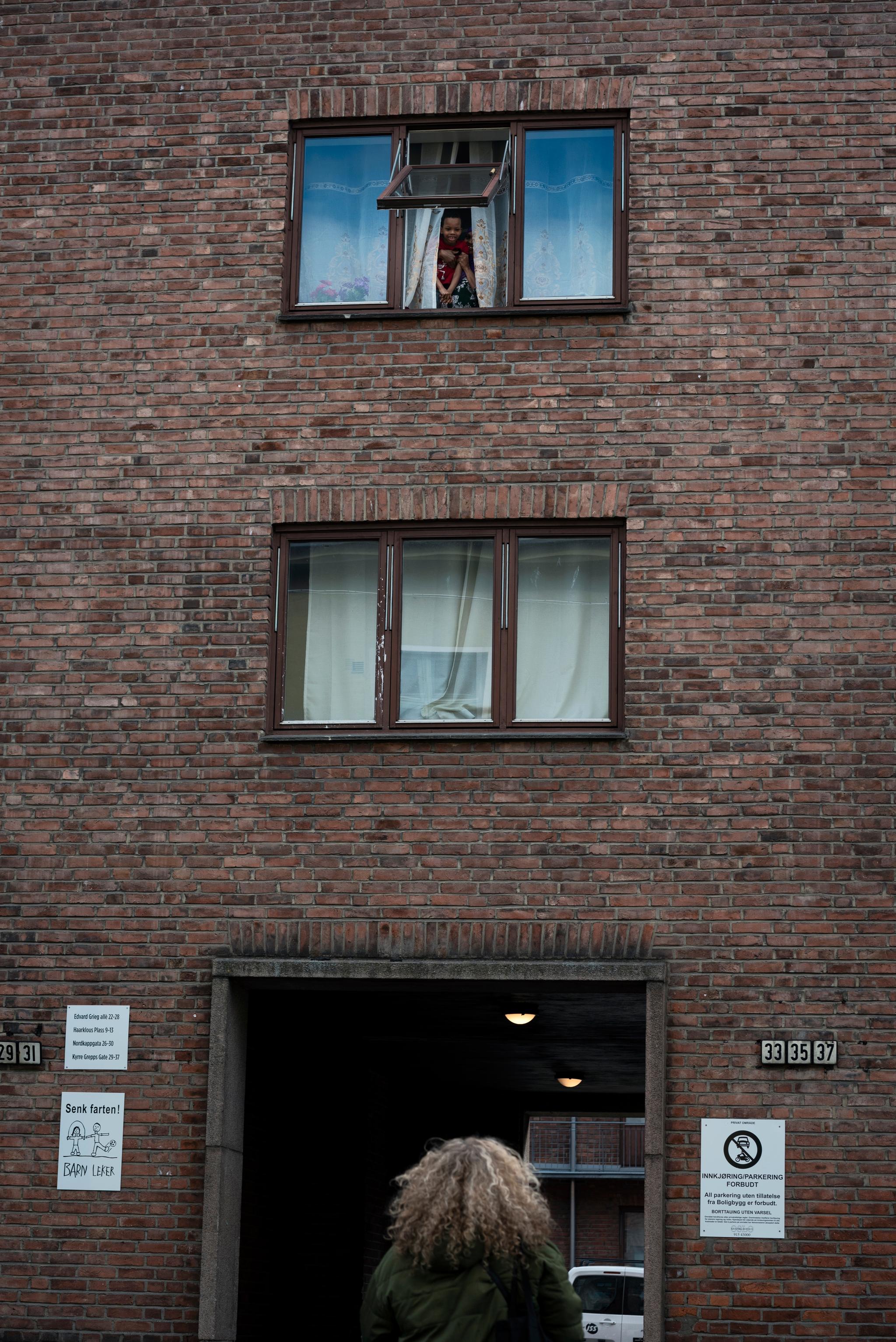 To barn titter ut av vinduet for å hilse på Cathrin Dahl Johansen, som de kjenner fra før. 