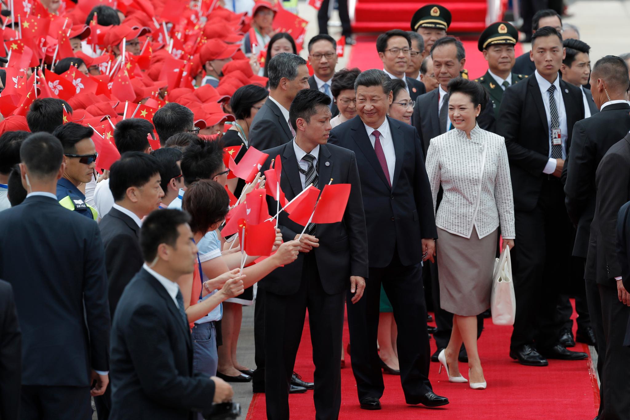 President Xi Jinping og Kinas førstedame Peng Liyuan ble mottatt av en menneskemasse med røde flagg da de torsdag formiddag kom til flyplassen i Hongkong. 