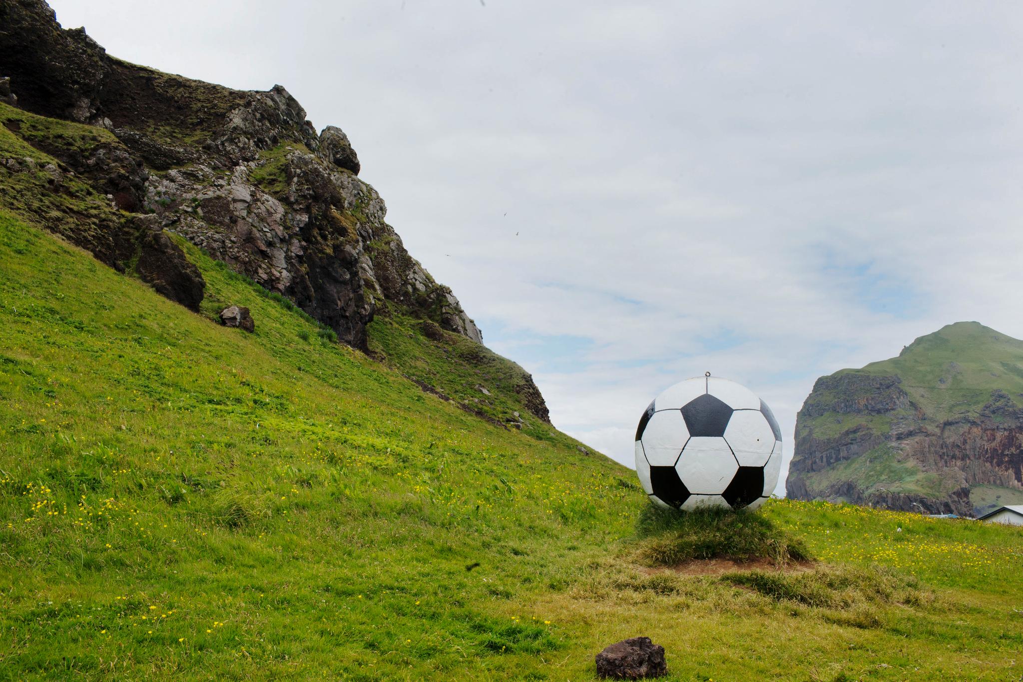 En liten gåtur fra sentrum over åskammen ligger inngangsporten til idrettsanlegget Hásteinsvöllur på den lille øygruppen Vestmannaeyjar utenfor sørkysten av Island. En stor fotball ved inngangen markerer hva som er i sentrum nå. 