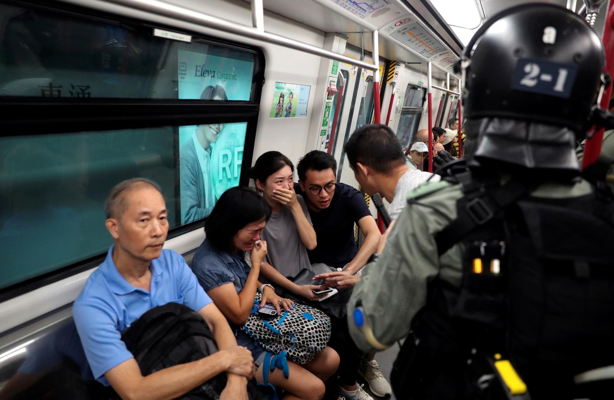 Jobbpendlere reagerer da politifolk kommer inn i en T-banevogn for å se etter demonstranter.