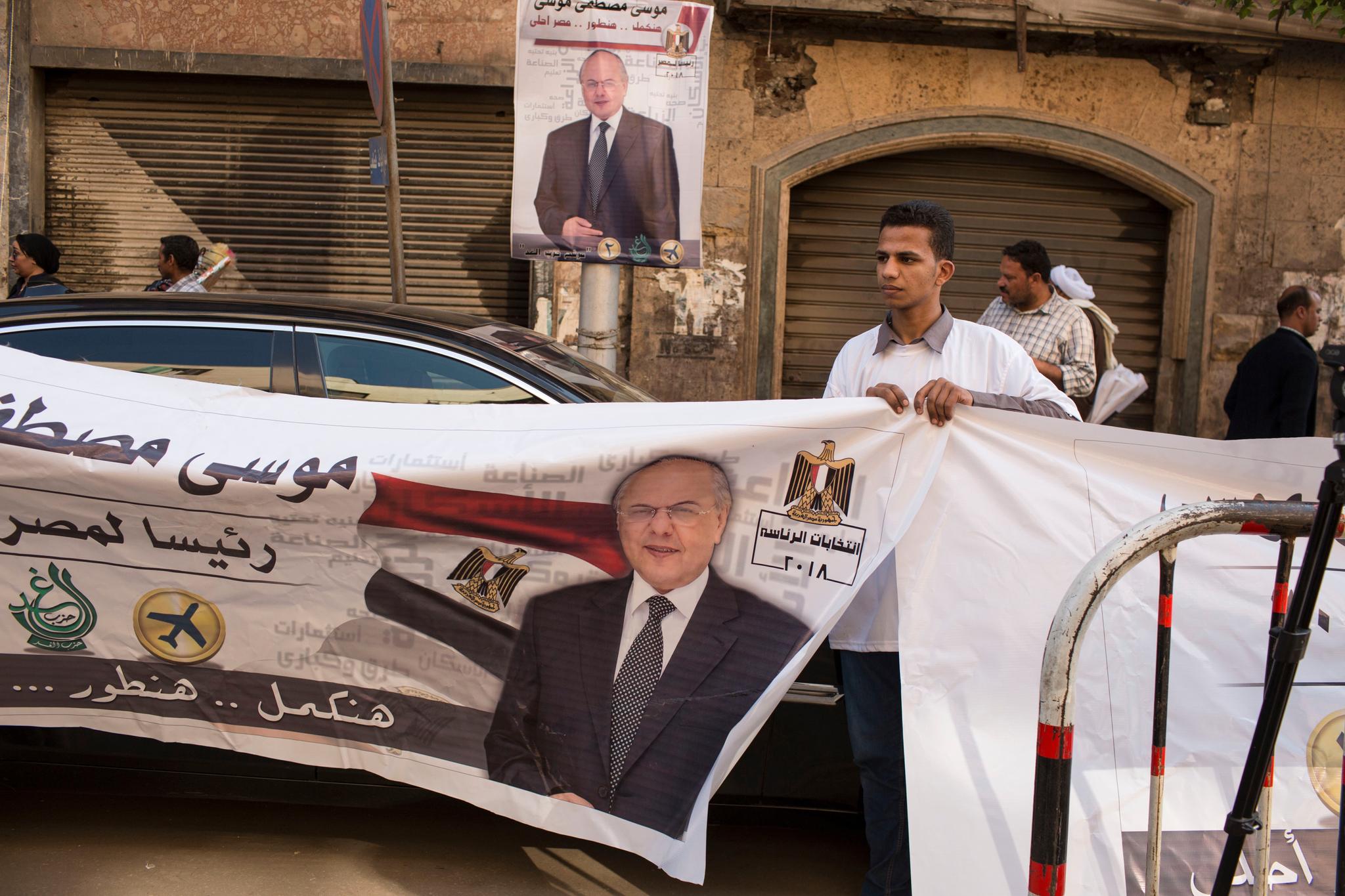 Var det her det skulle være demonstrasjon? En håndfull personer holder opp valgplakater mens Moussa Moustafa Moussa tar en tur utenfor partikontoret for å snakke med pressen den 10. mars. «Vi vil gå videre, vi vil utvikle oss, Egypt vil bli vakrere», står det på plakaten.