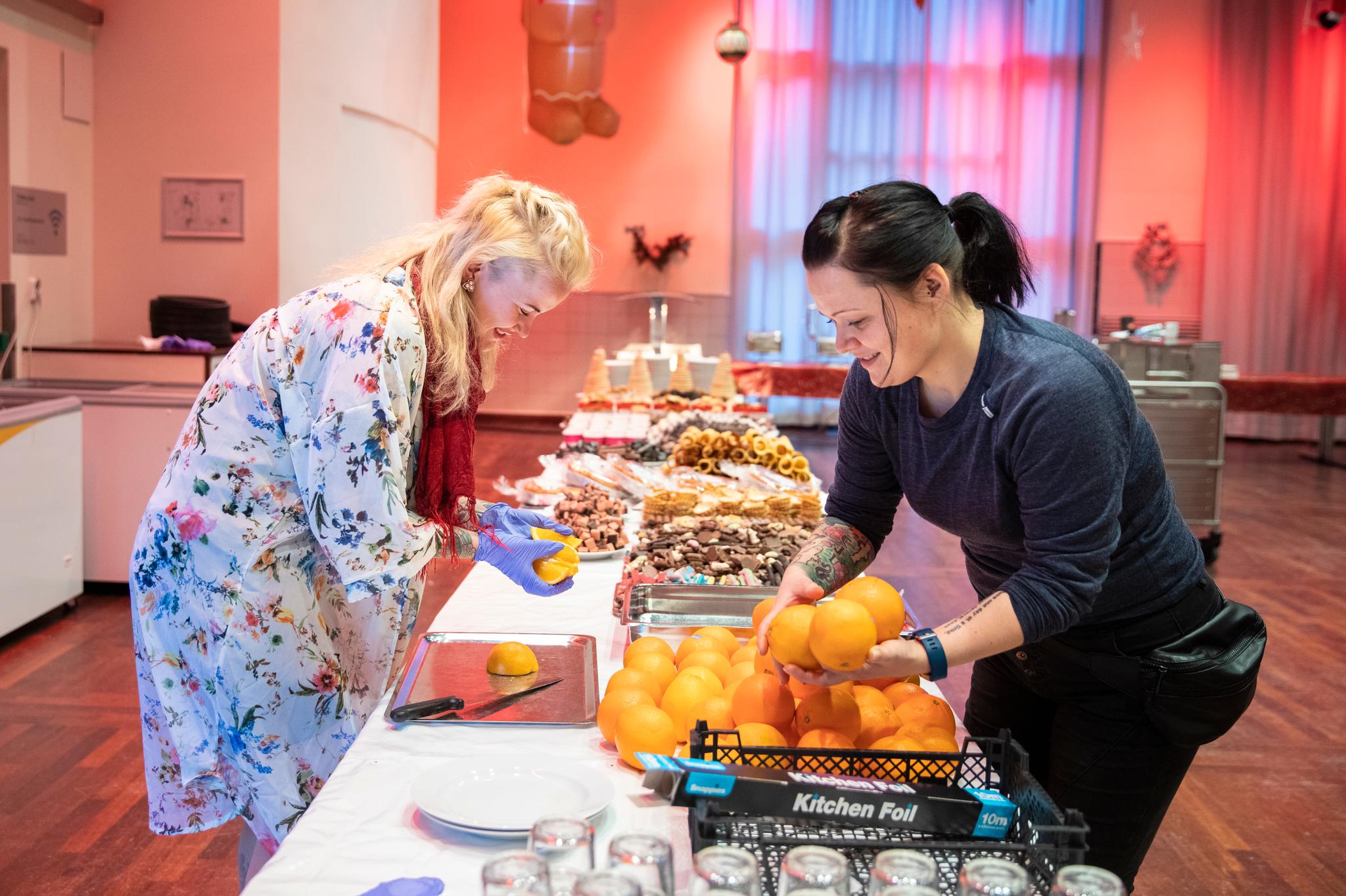Kakebordet begynner å bli klart. Julie Høivik (til venstre) og Christin Lid ordner frukten. Tre til fire paller frukt og grønnsaker er donert til arrangementet.