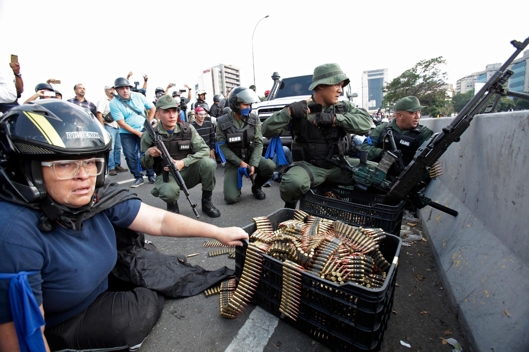 En demonstrant fra opposisjonssiden ved siden av noen av soldatene som tirsdag byttet side i konflikten i Venezuela. 