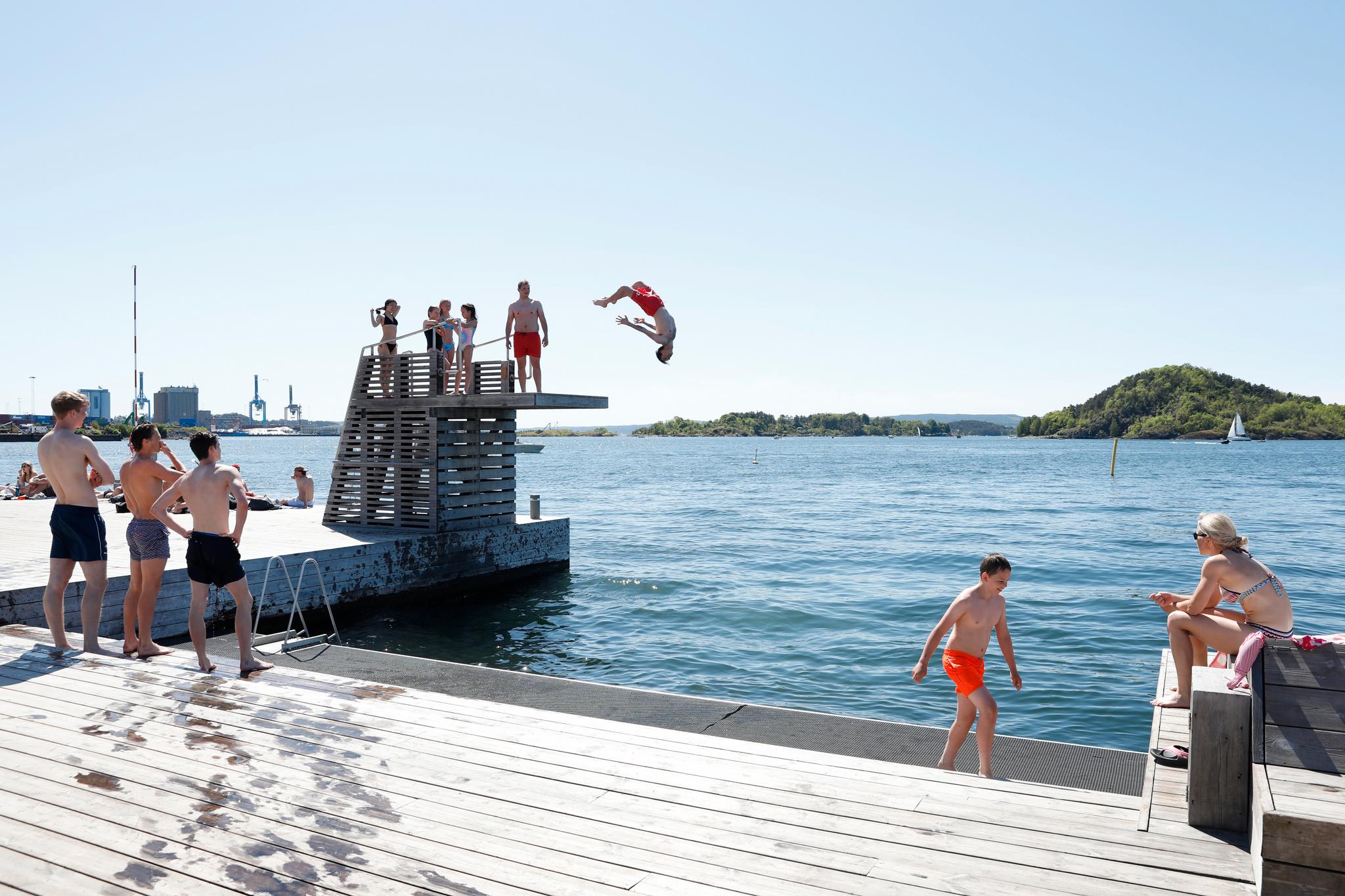 På selve sjøbadet, som passes på av vakter, er det god plass. Sebastian Berg Isdahl flyr ut i vannet, mens kompisen Nikolai Hammerseth (også i rød shorts) venter på tur.