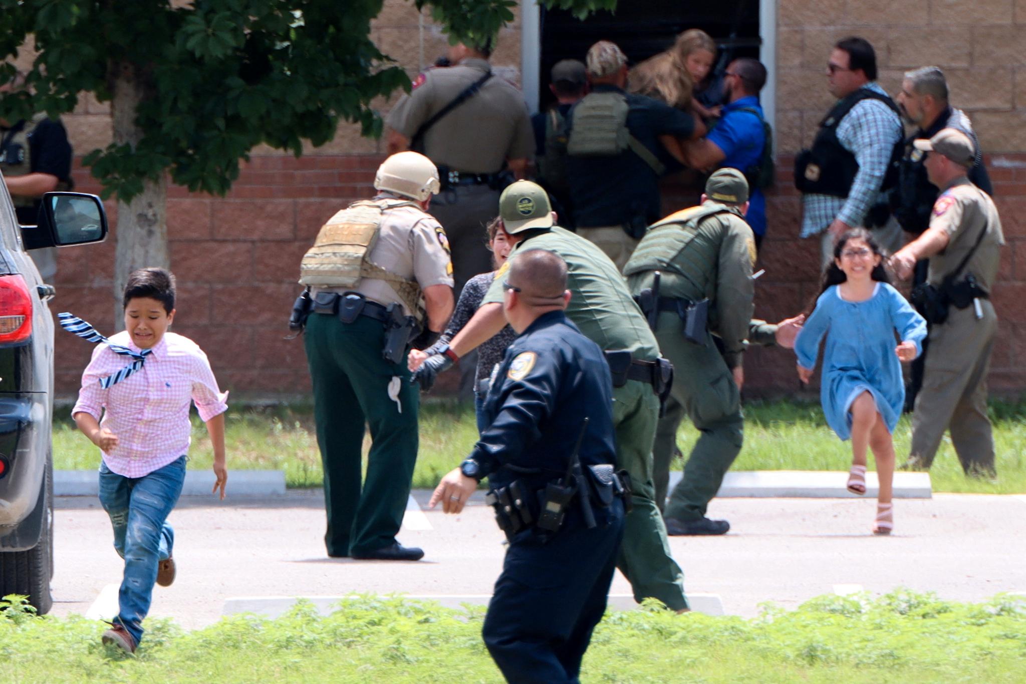Barn løper i sikkerhet etter å ha hoppet ut av et vindu på Robb Elementary School. 