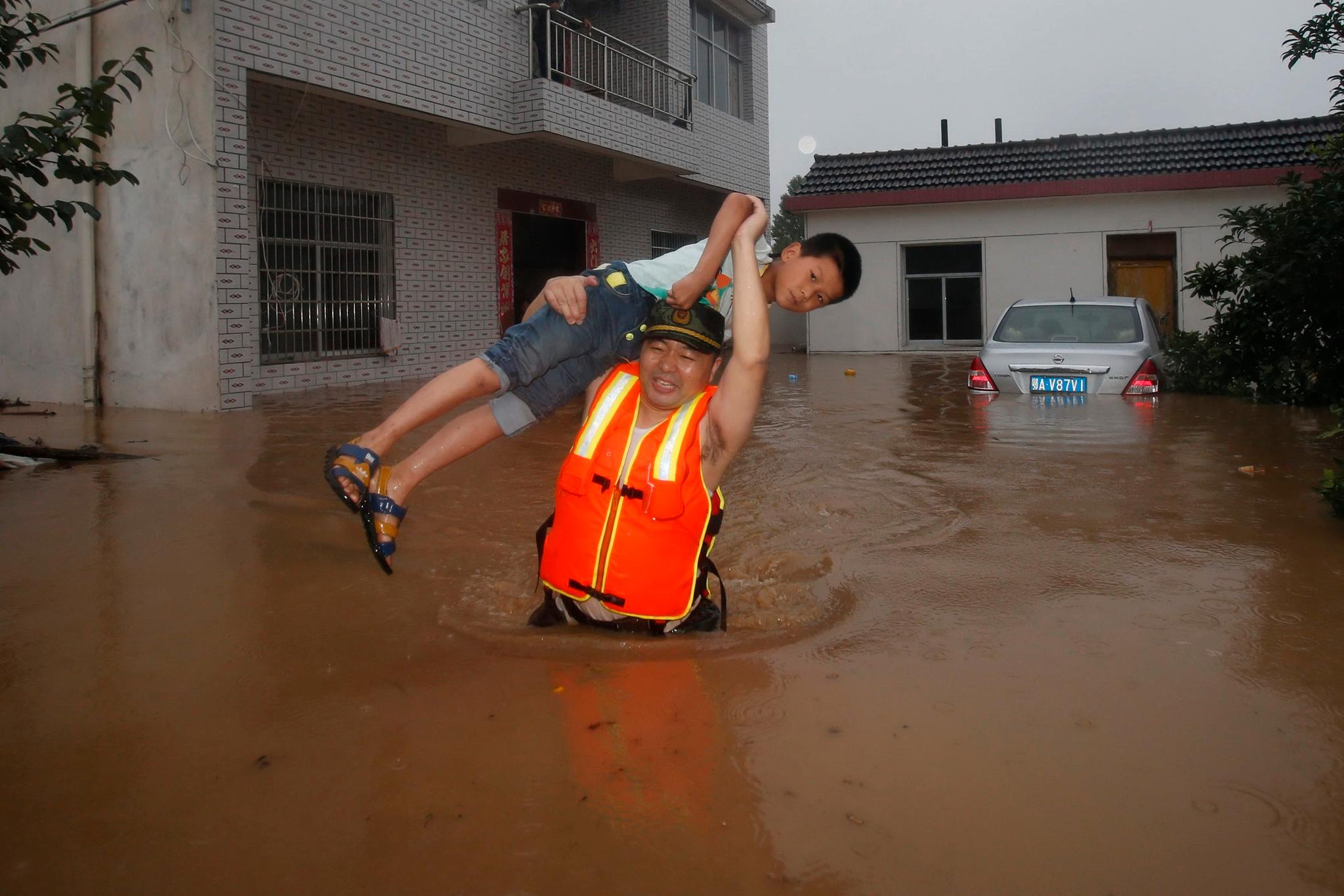 En redningsarbeider bærer et barn gjennom flomvann i Wuhan i Hubei-provinsen.
