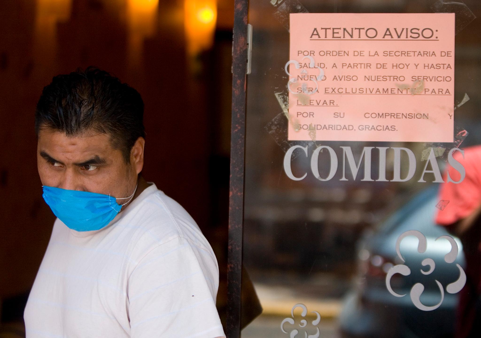 Svineinfluensaen i 2009 førte til en rekke tiltak mot smittespredning, deriblant i Mexico. Skiltet bak kelneren med maske opplyser at restauranten etter ordre fra helsemyndighetene inntil videre bare vil tilby take away-mat.