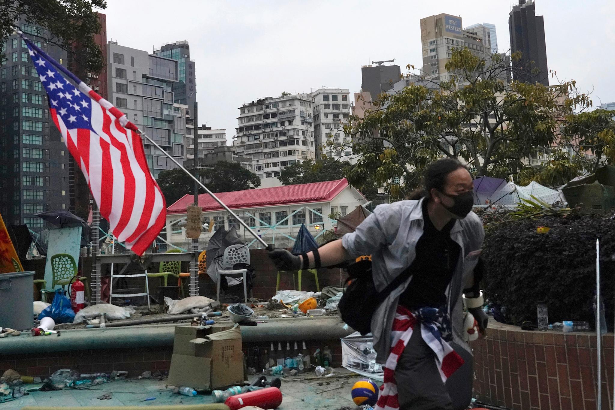 En demonstrant flagger med et amerikansk flagg ved Hongkongs tekniske universitet onsdag 20. november. En gruppe demonstranter forskanser seg fremdeles på universitetsområdet. 