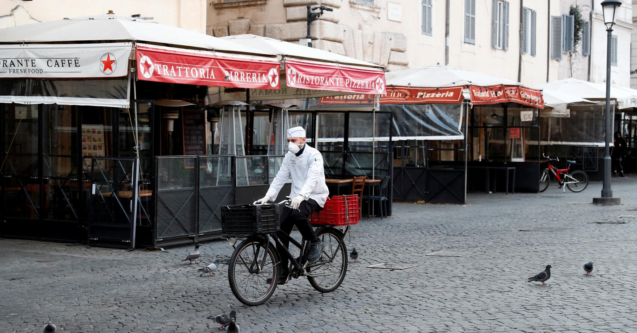 Et ensomt sykkelbud med maske på en øde Campo de Fiori i Roma. Italia er første land i Europa som er satt under totalt porforbud siden krigen.