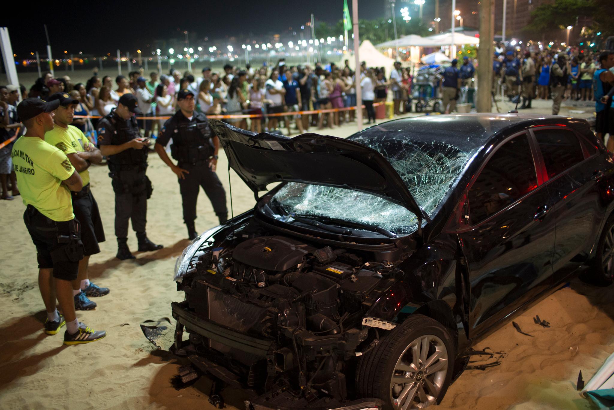 Politifolk står ved siden av bilen som kjørte inn i en folkemengde på Copacabana. 
