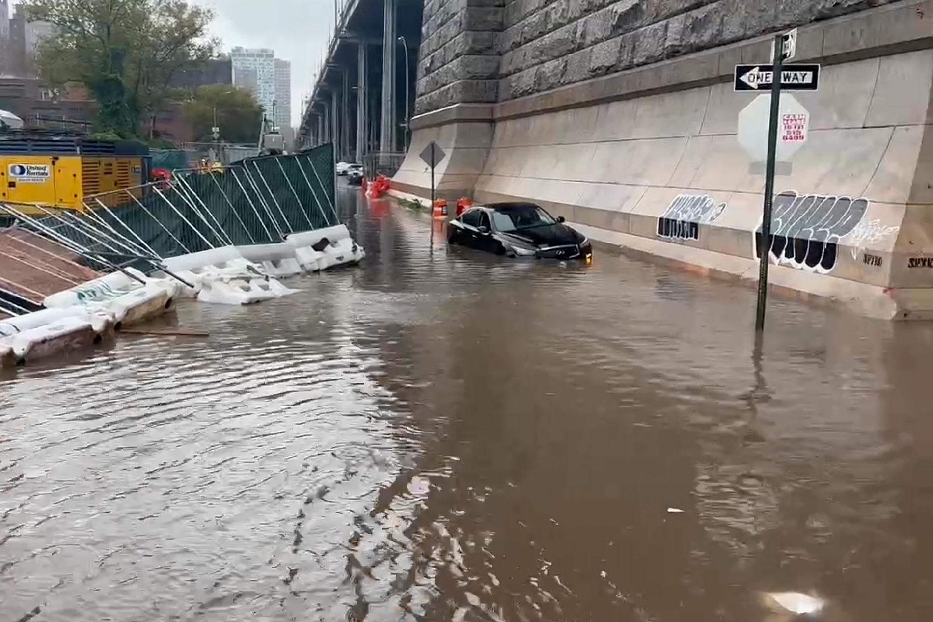 En bil står parkert ved Williamsburg-broen idet New York er rammet av kraftige oversvømmelser. 
