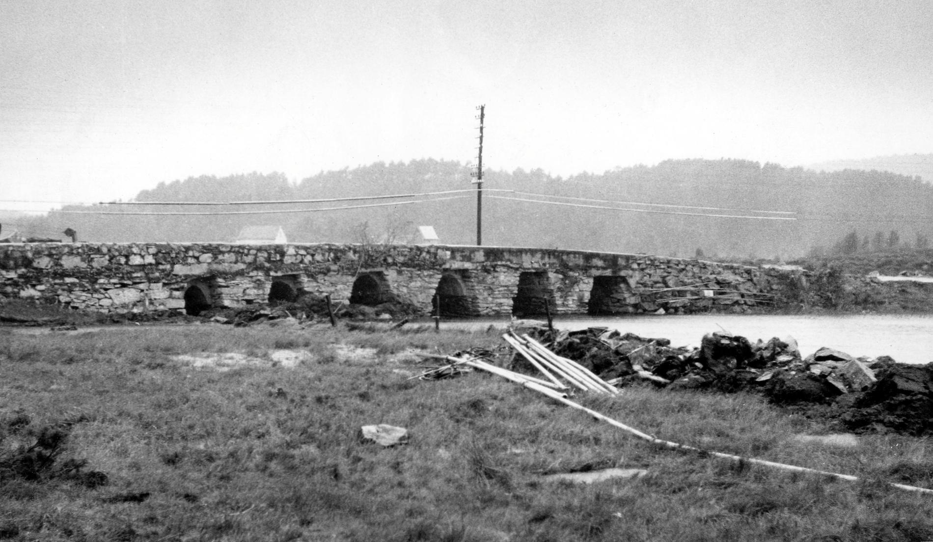 HÅBROEN: Dette bildet er trolig tatt i 1957 og viser Håbroen eller Rollands bro. Håbroen var en såkalt platebro, med store steinheller eller plater liggende over brokarene. Håbroen sto ferdig i 1808 og var bygget av Mons Hansen Vesterli. Den lå omtrent der Litleåsvegen begynner, men ble sprengt bort i 1960 i forbindelse med kanaliseringen av åsamyrane. 