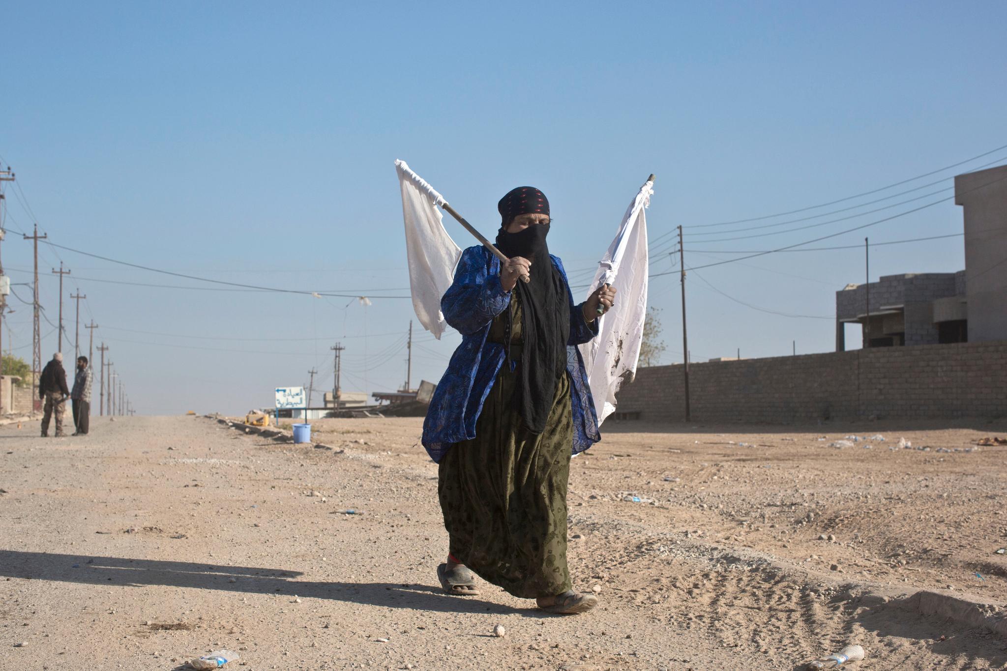 En kvinne bærer hvite flagg mens hun flykter fra en konfliktsone i den østlige delen av Mosul.