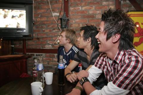 Stian Meling (f.v.), Phuong Ba Nguyen og Duc Ly Minh ser fotball på tv-skermen på utestedet