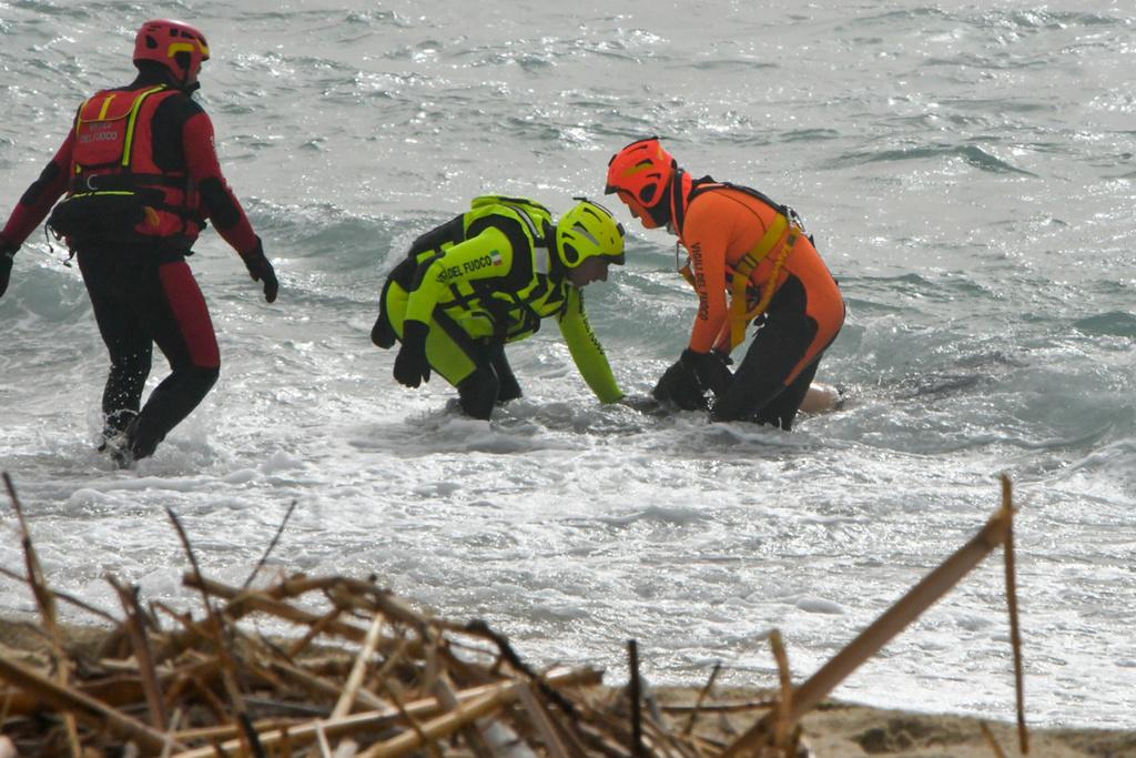 Redningsmannskaper drar en omkommet person opp av havet etter forliset for tre uker siden.