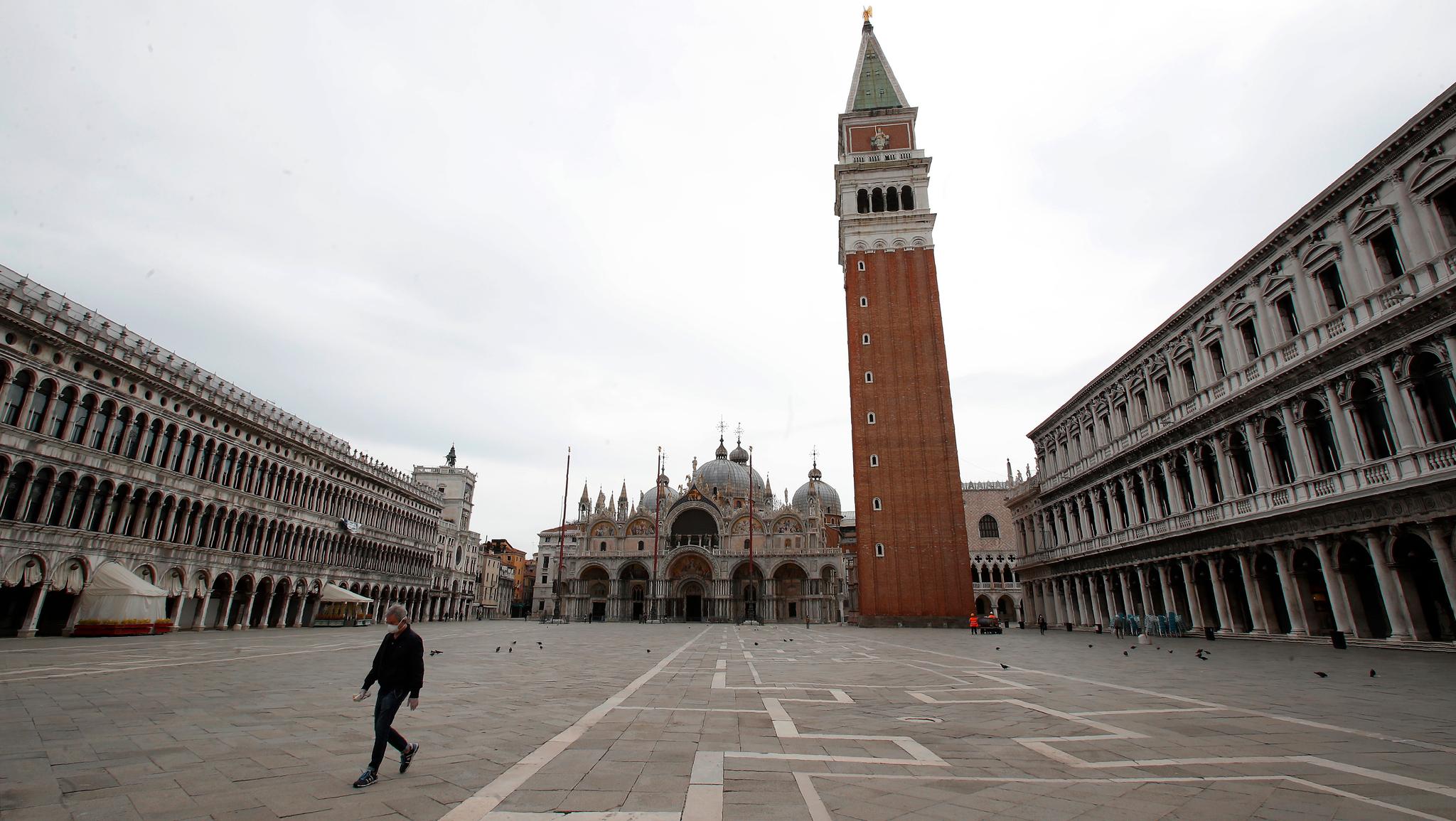 En enslig mann går over den tomme Markusplassen i Venezia.
