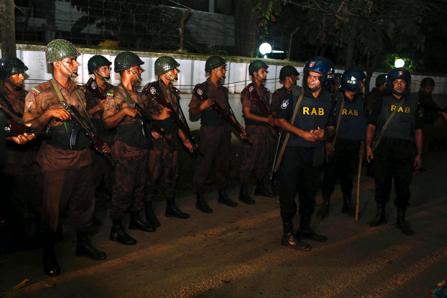 Sikkerhetsstyrker utenfor restauranten der væpnede menn tok seg inn fredag kveld i Dhaka, hovedstaden i Bangladesh.