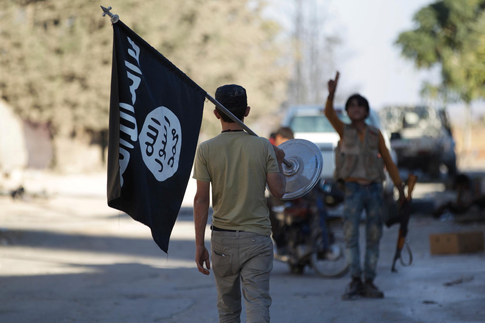 En opprører bærer et flagg erobret fra IS-styrker nord i Aleppo-provinsen tidligere denne uken.