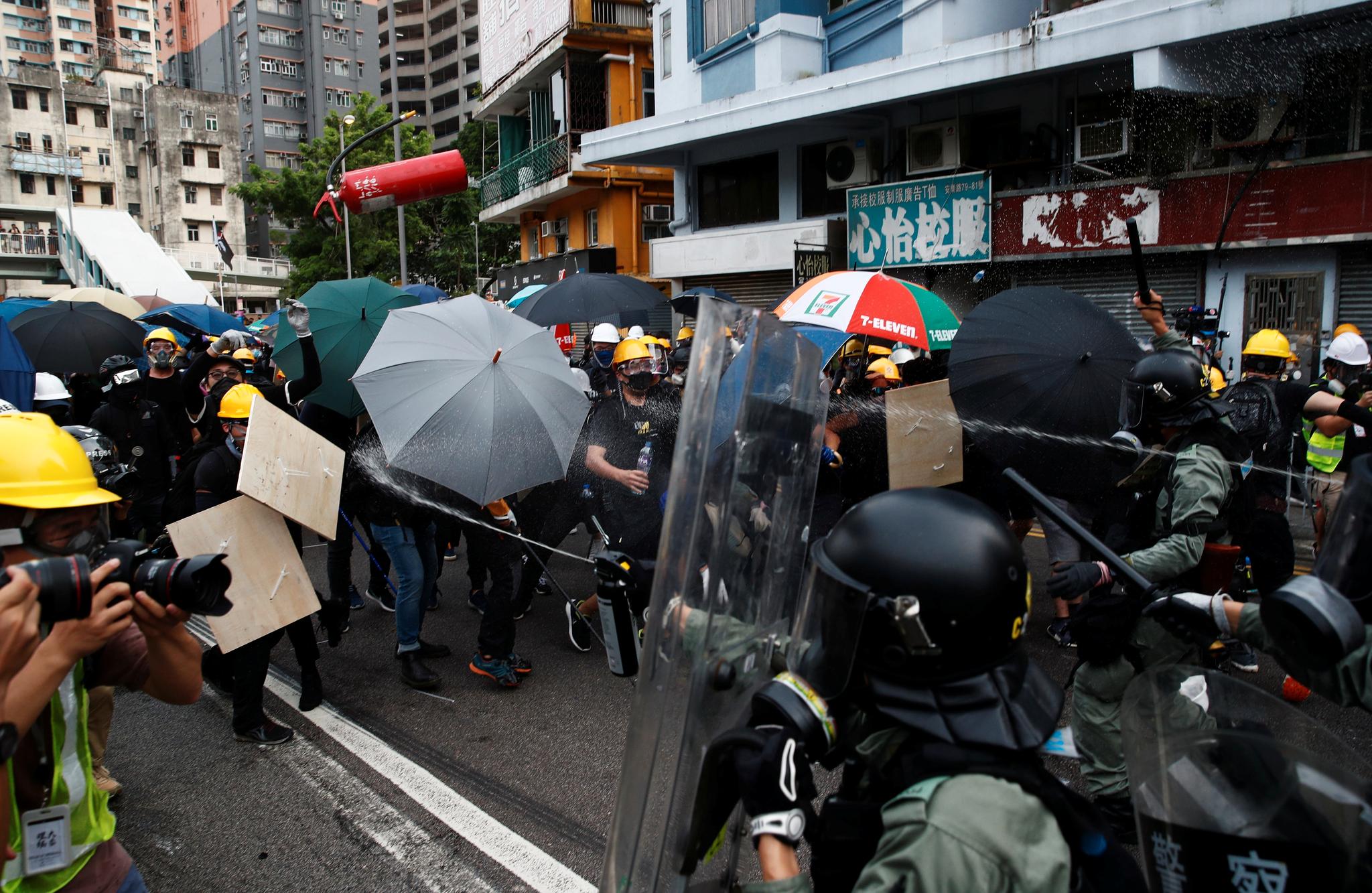 Politiet var lørdag formiddag inneklemt av demonstranter med paraplyer. 