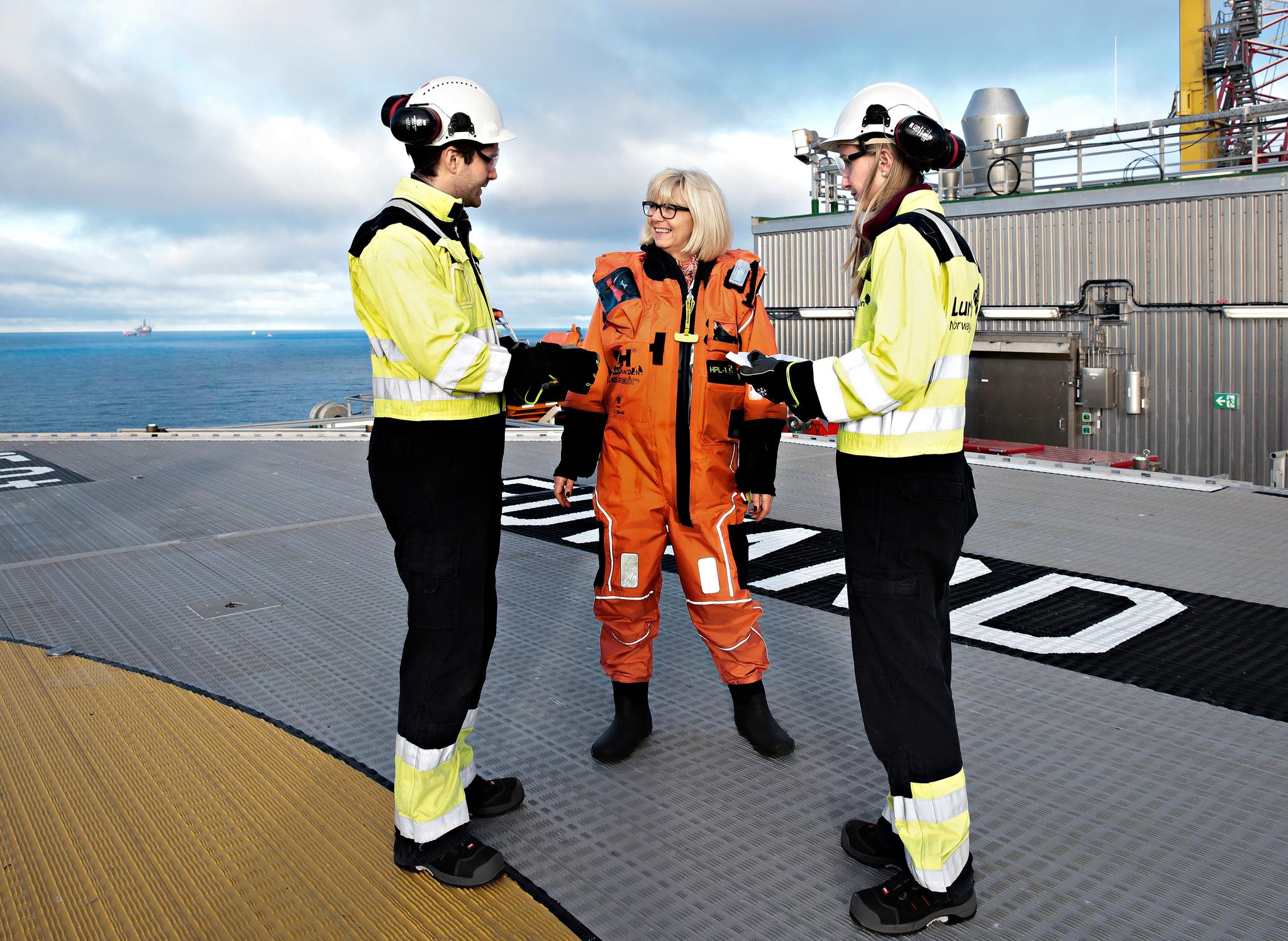 Lundin-sjef Kristin Færøvik står på helikopterdekket på Edvard Grieg-plattformen sammen med Jørgen Ernstsen og Tonje L. Bjerga. Studentene er to av tre vinnere i Lundins innovasjonskonkurranse.