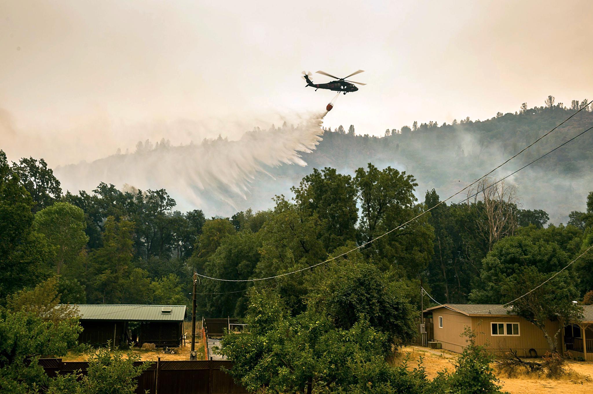 Helikopter vannbomber New Long Valley Road i Lake County, men flammene har godt tak i den tørre vegetasjonen.