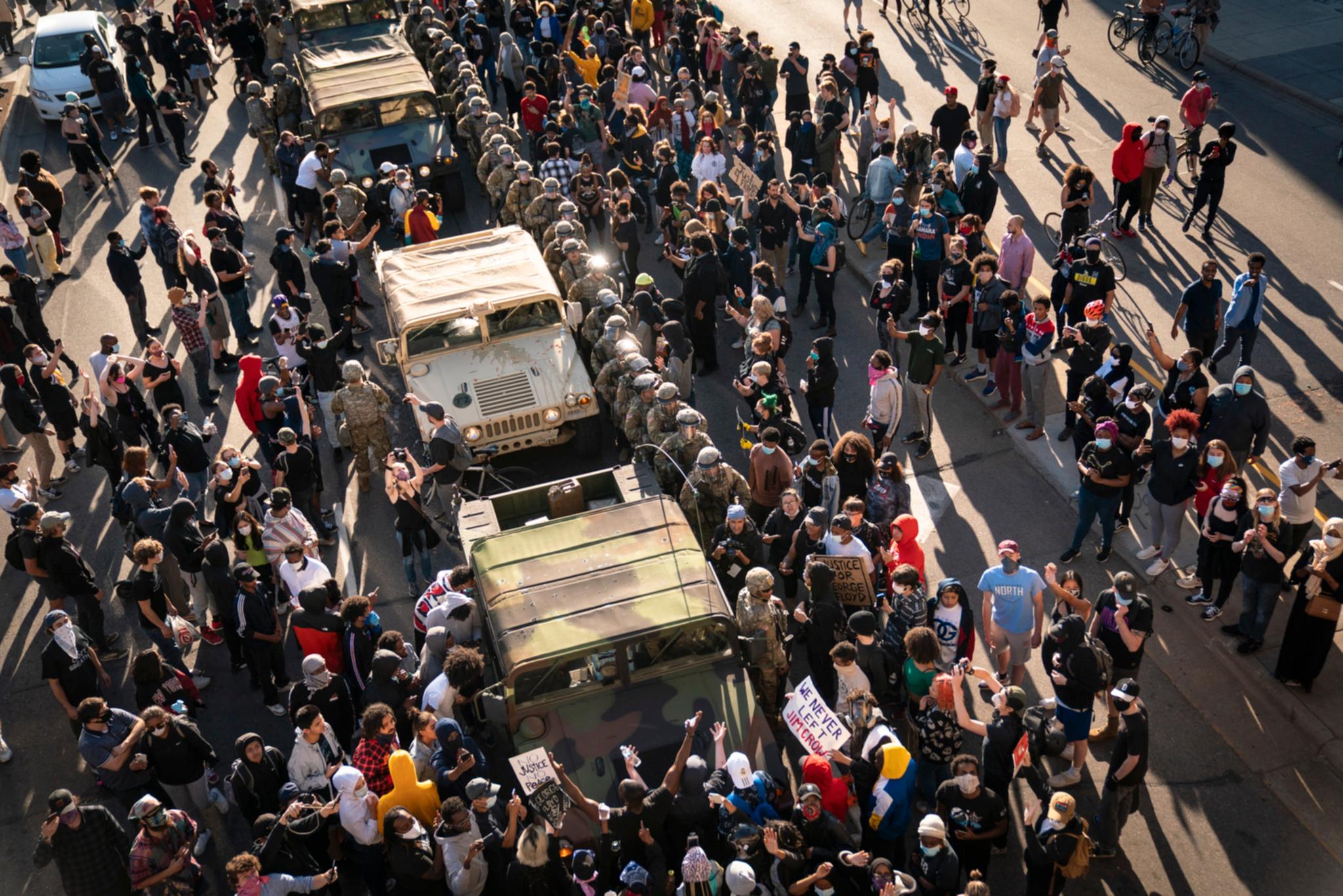 Demonstranter omringer flere militære kjøretøy i Minneapolis, Minnesota fredag.