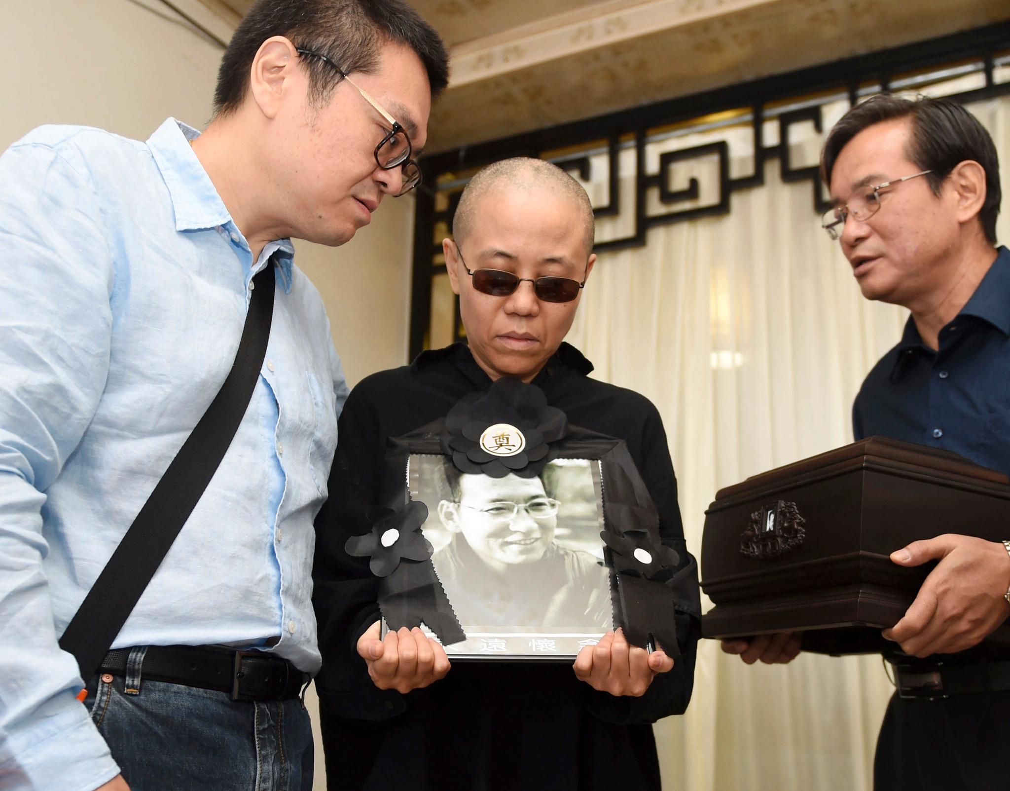 Liu Xia holder et bilde av sin mann Liu Xiaobo under hans begravelse for et år siden. 